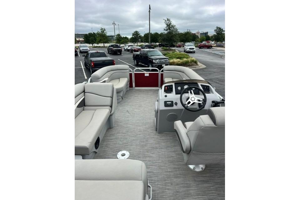 2021 Bennington 205SL pontoon boat interior with seating and steering wheel in parking lot.