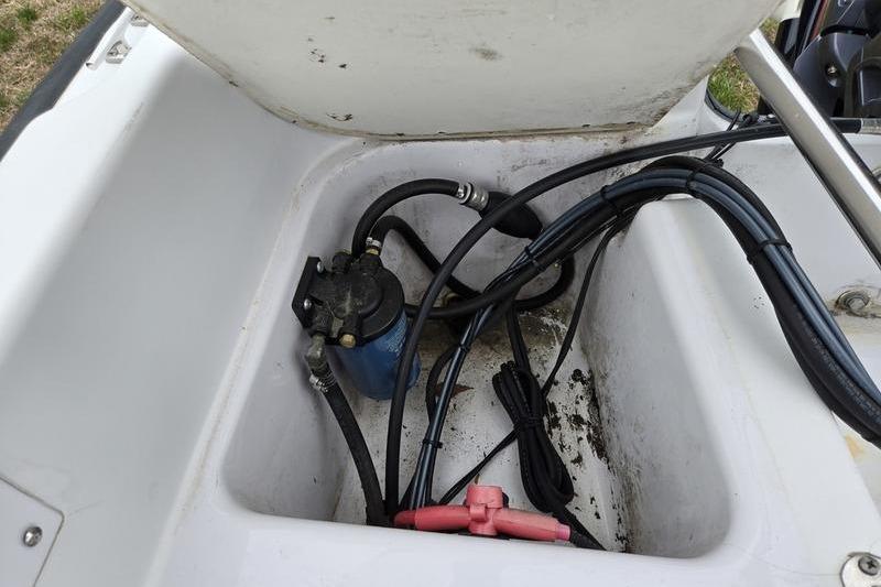 Open storage compartment of a 1996 Boston Whaler Outrage 17 boat, showing cables and equipment.