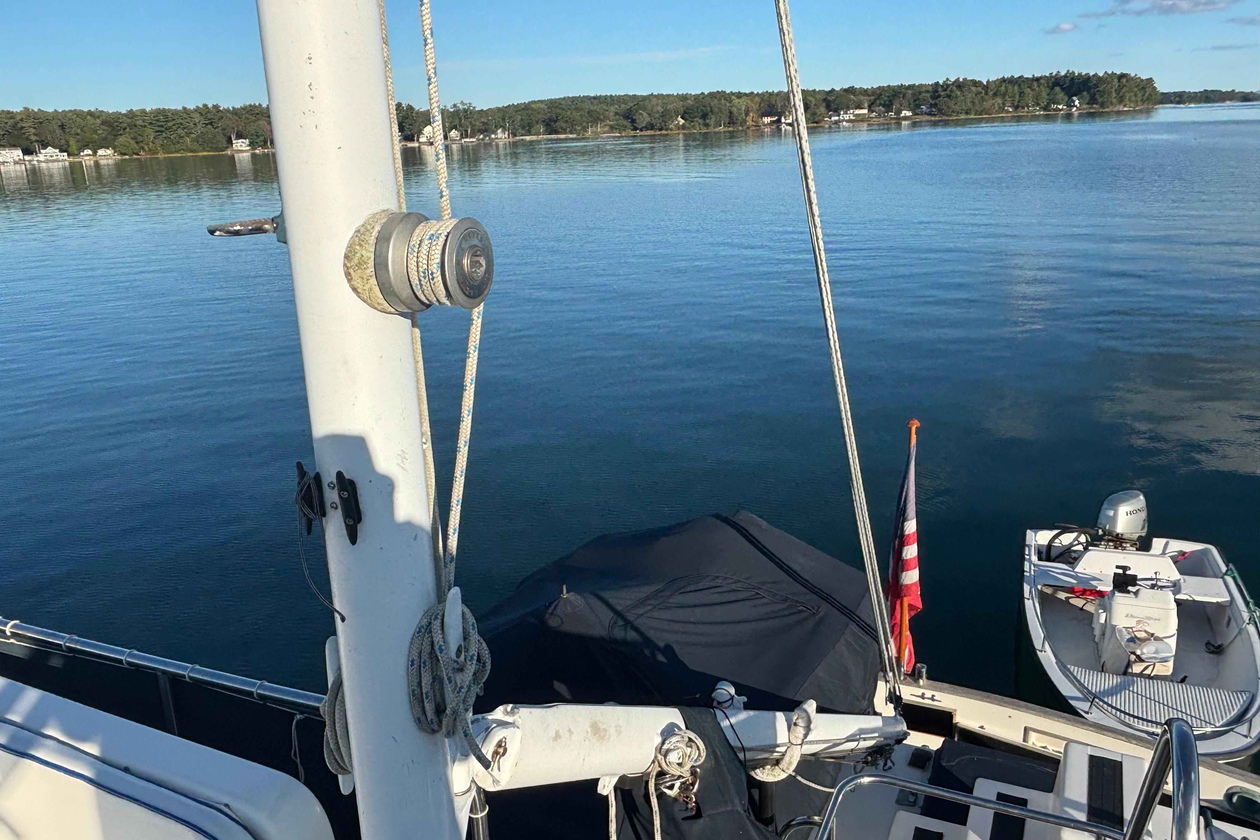 1989 Grand Banks 46 Classic yacht on serene lake with American flag and small boat.