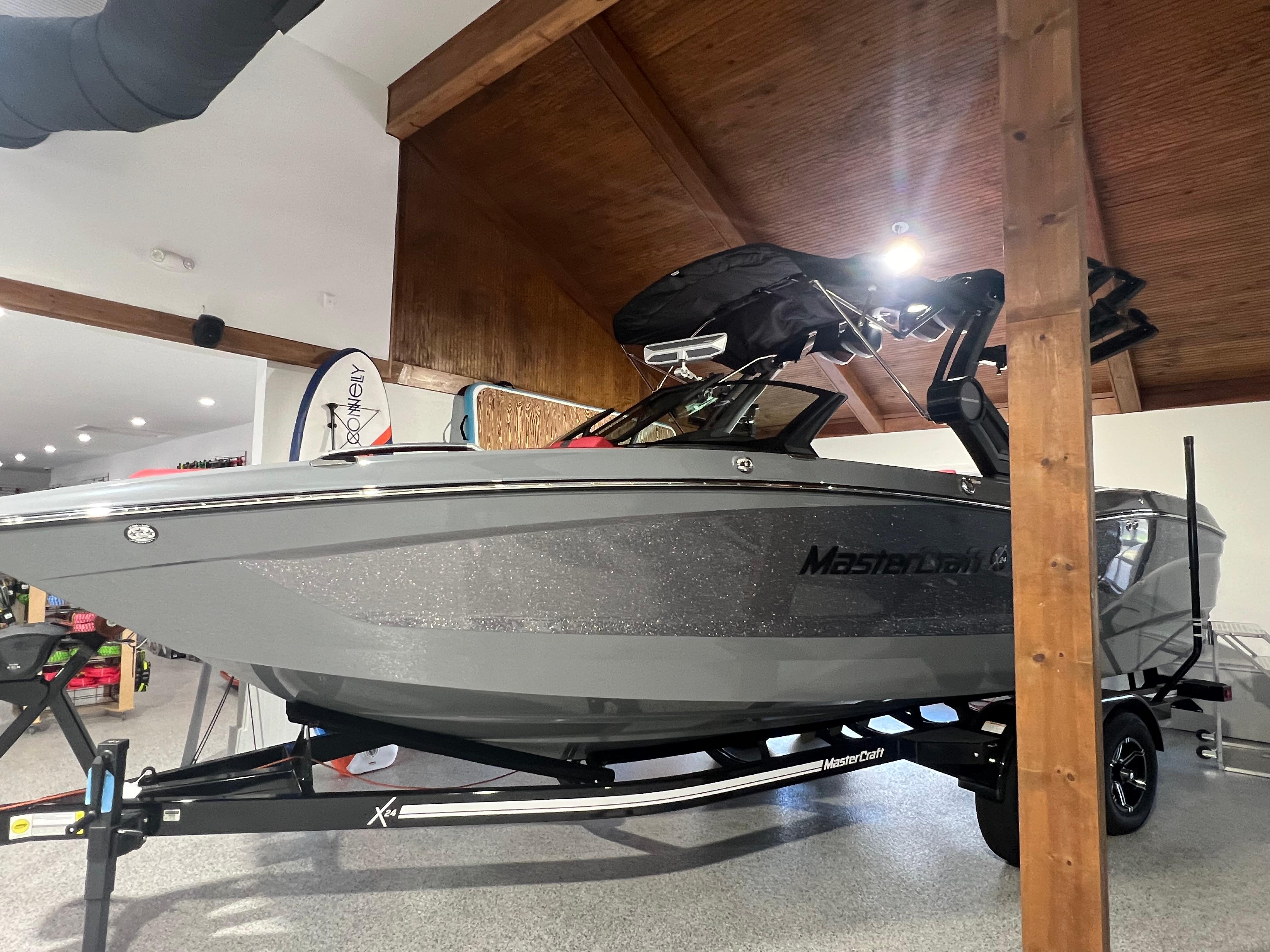 2025 MasterCraft X24 boat in showroom, sleek gray design on trailer.