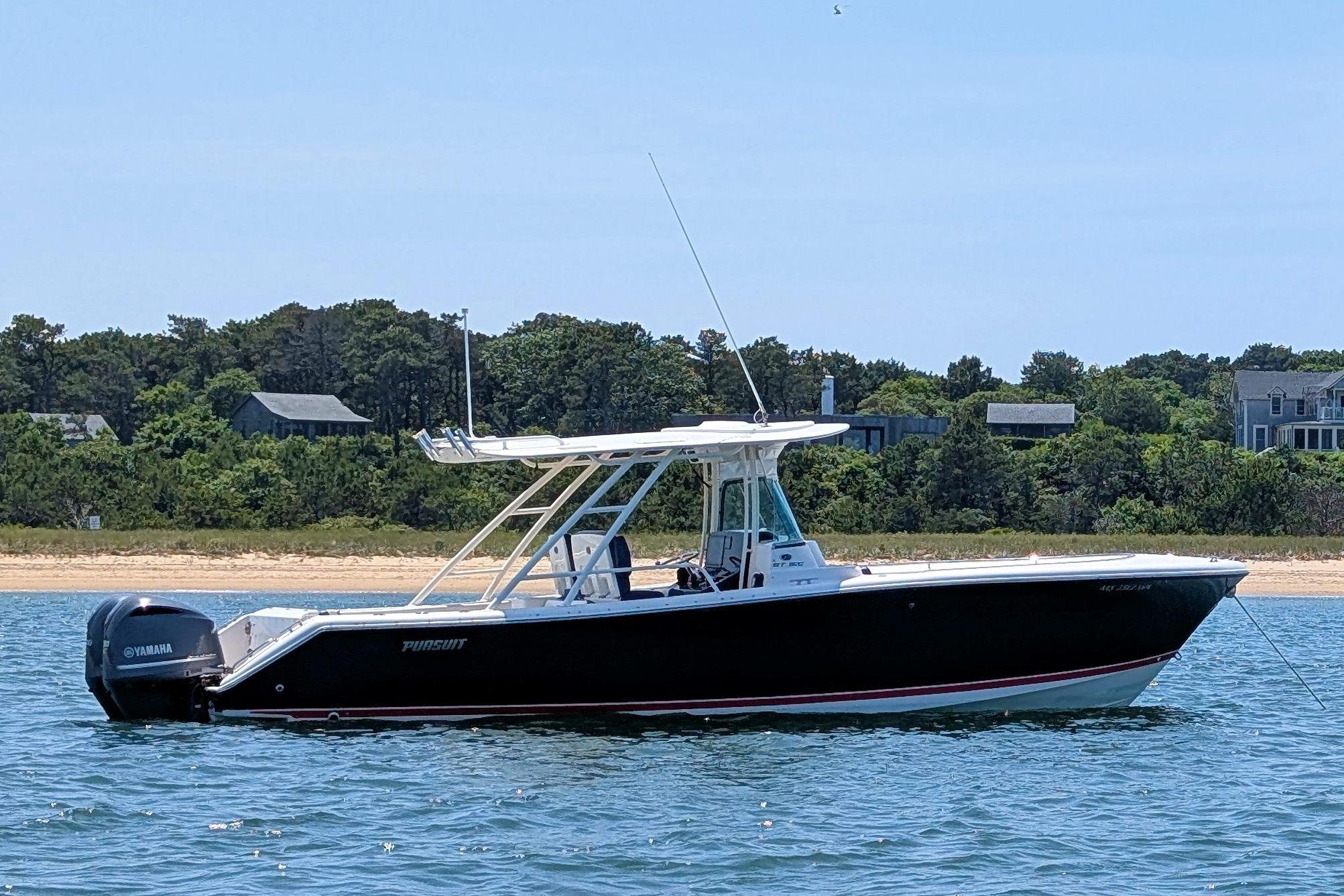 2013 Pursuit ST 310 Sport boat on water near a sandy shoreline.