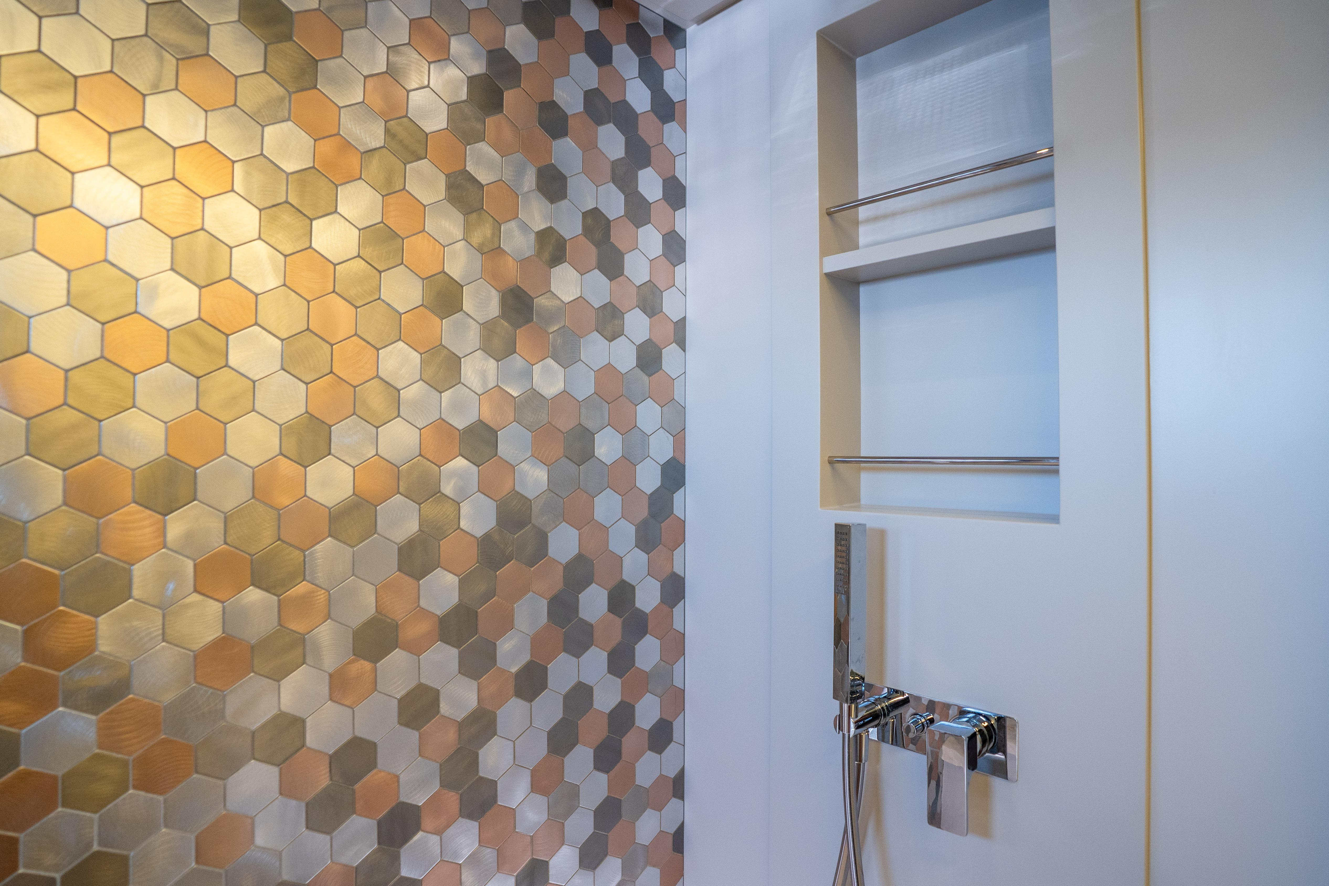 Luxurious bathroom with hexagonal metallic tiles in a 2024 Pershing 7X yacht.