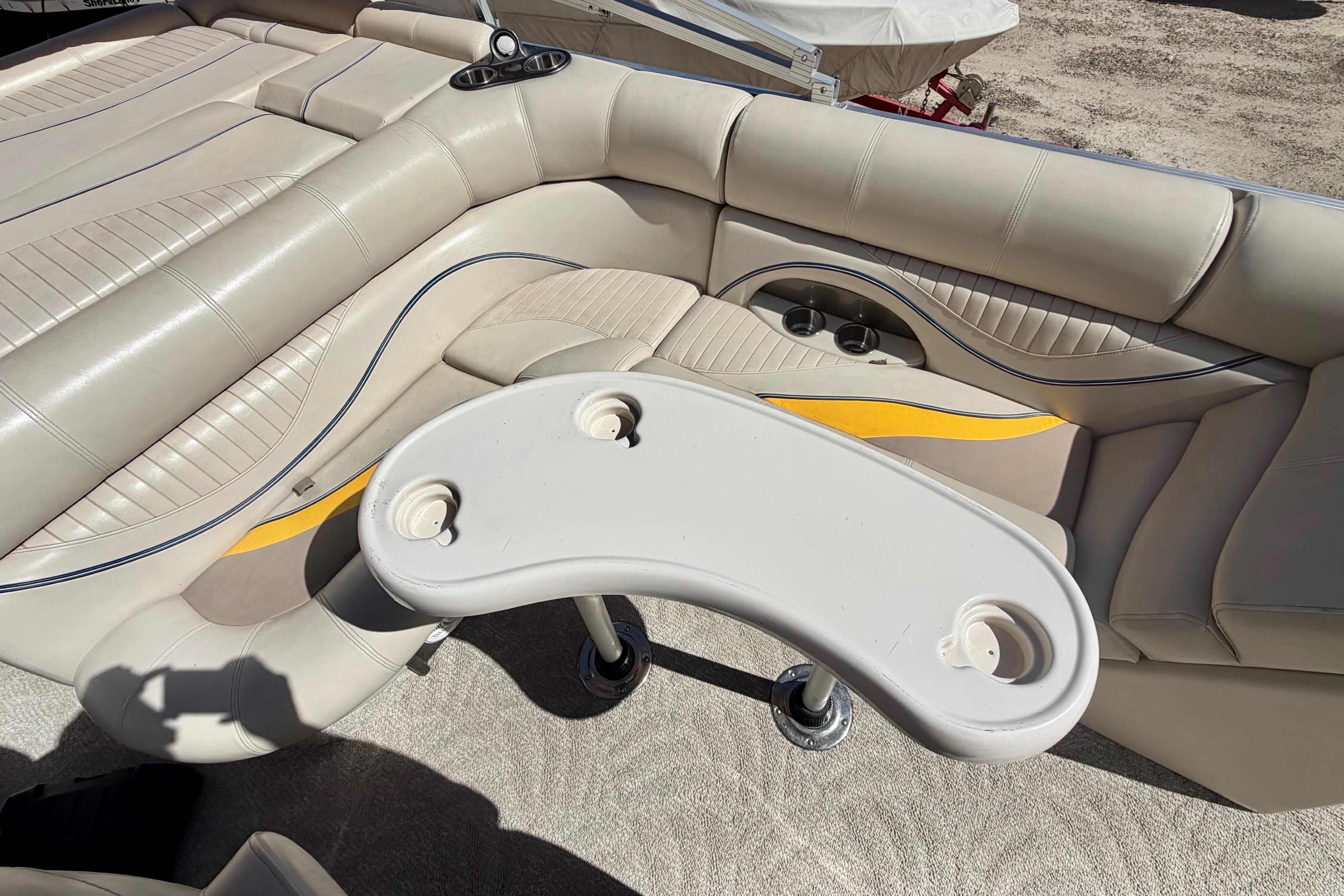 Luxurious seating area on a 2006 South Bay 925CR pontoon boat with cup holders and table.