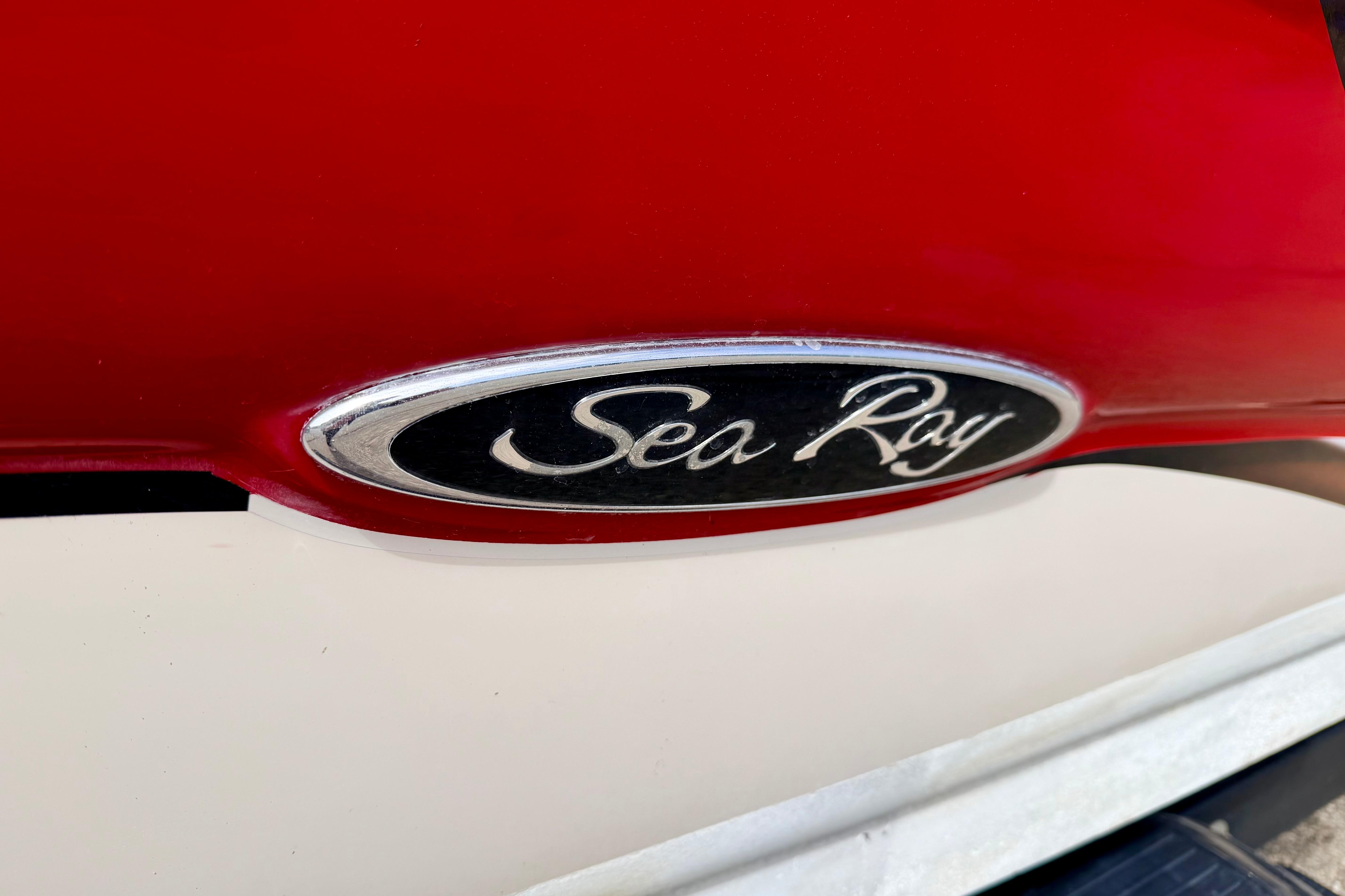 Close-up of 2003 Sea Ray 200 Sundeck logo on red and white boat.
