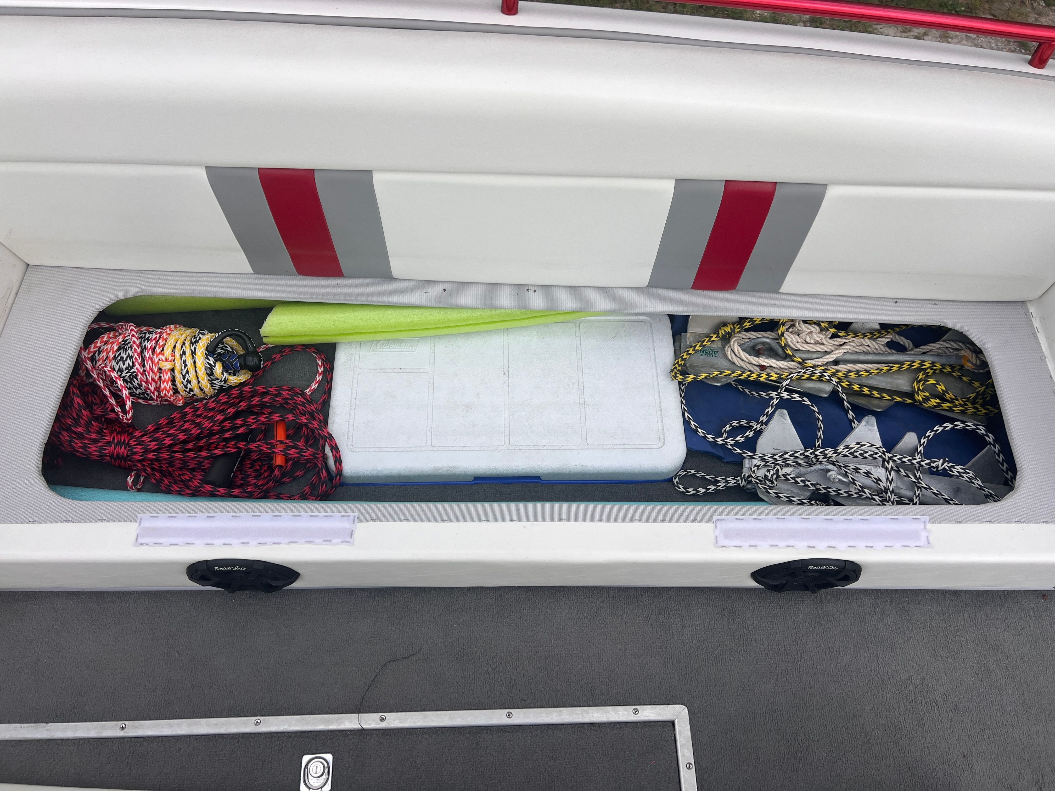 An open storage compartment with ropes and a paddle.