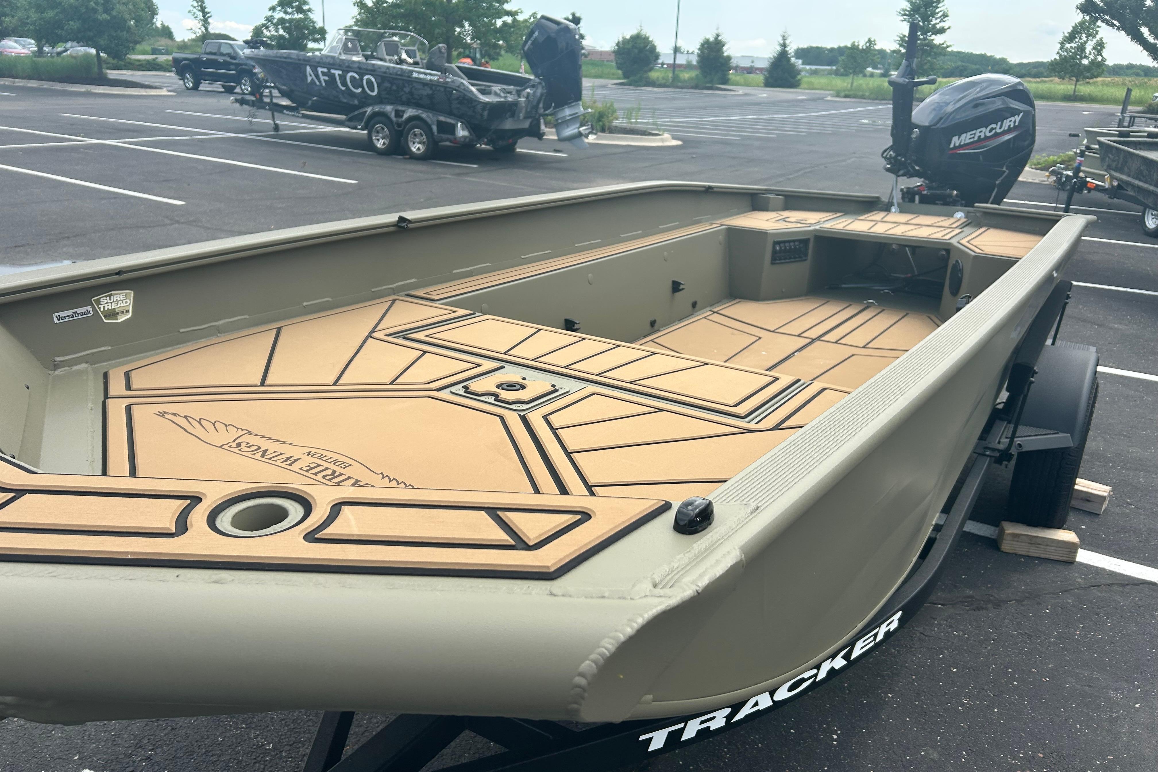 2026 Tracker Grizzly 1650 T Prairie Wings Edition boat in parking lot, featuring spacious deck.