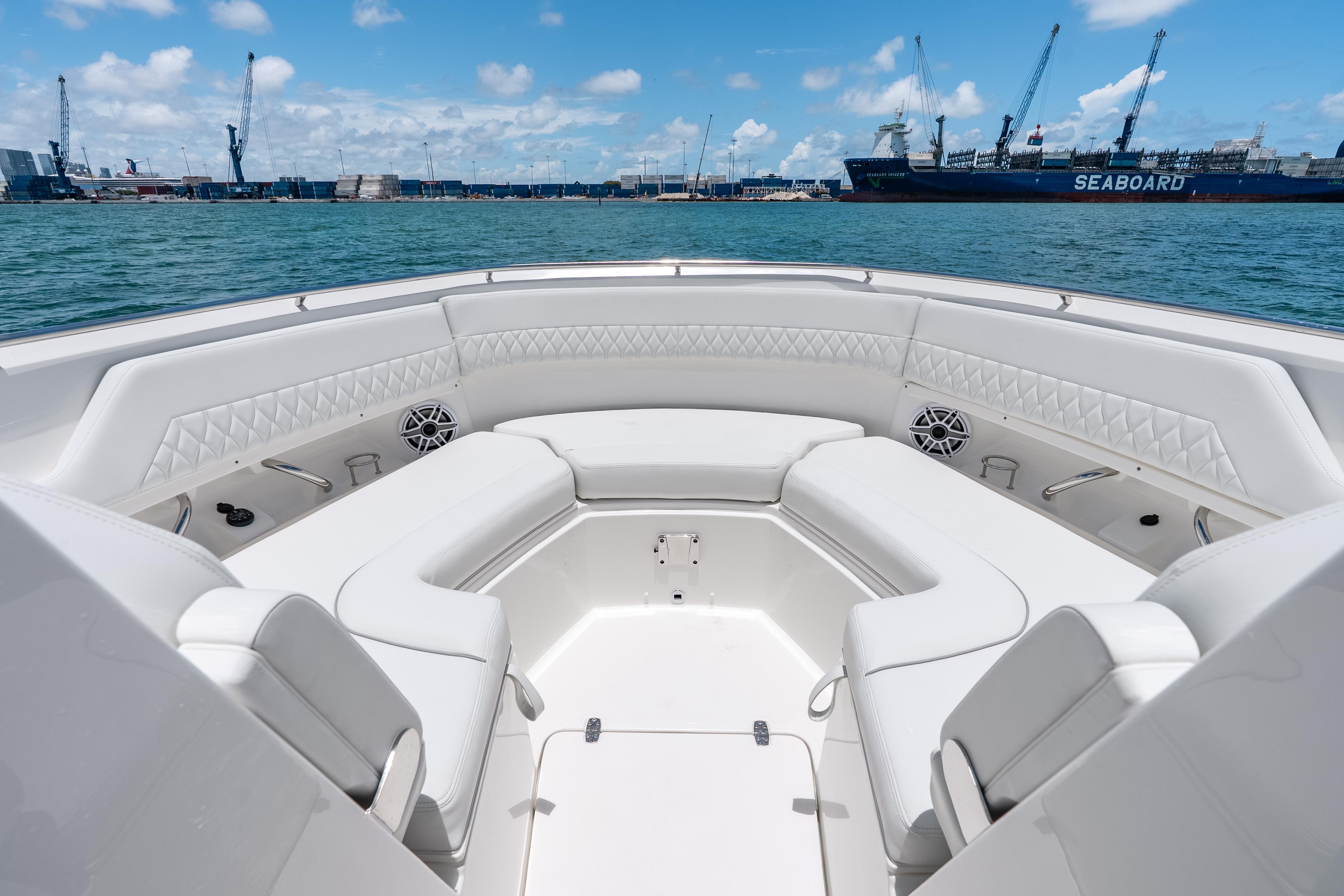 Luxurious seating on 2026 Pursuit DC 326 Dual Console boat, docked in a bustling harbor.