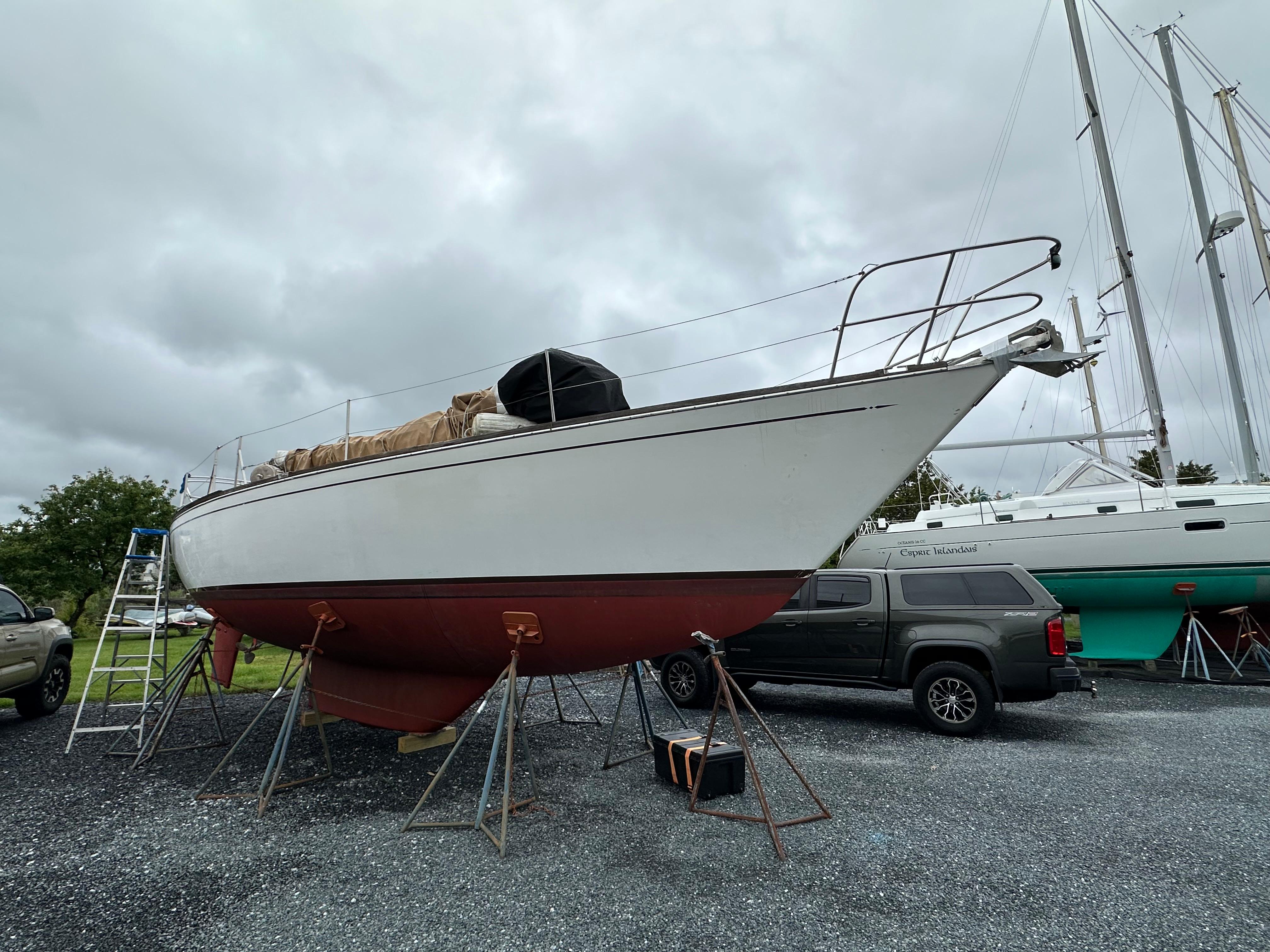 1981 Tartan 37 sloop on stands, overcast sky, parked truck nearby.