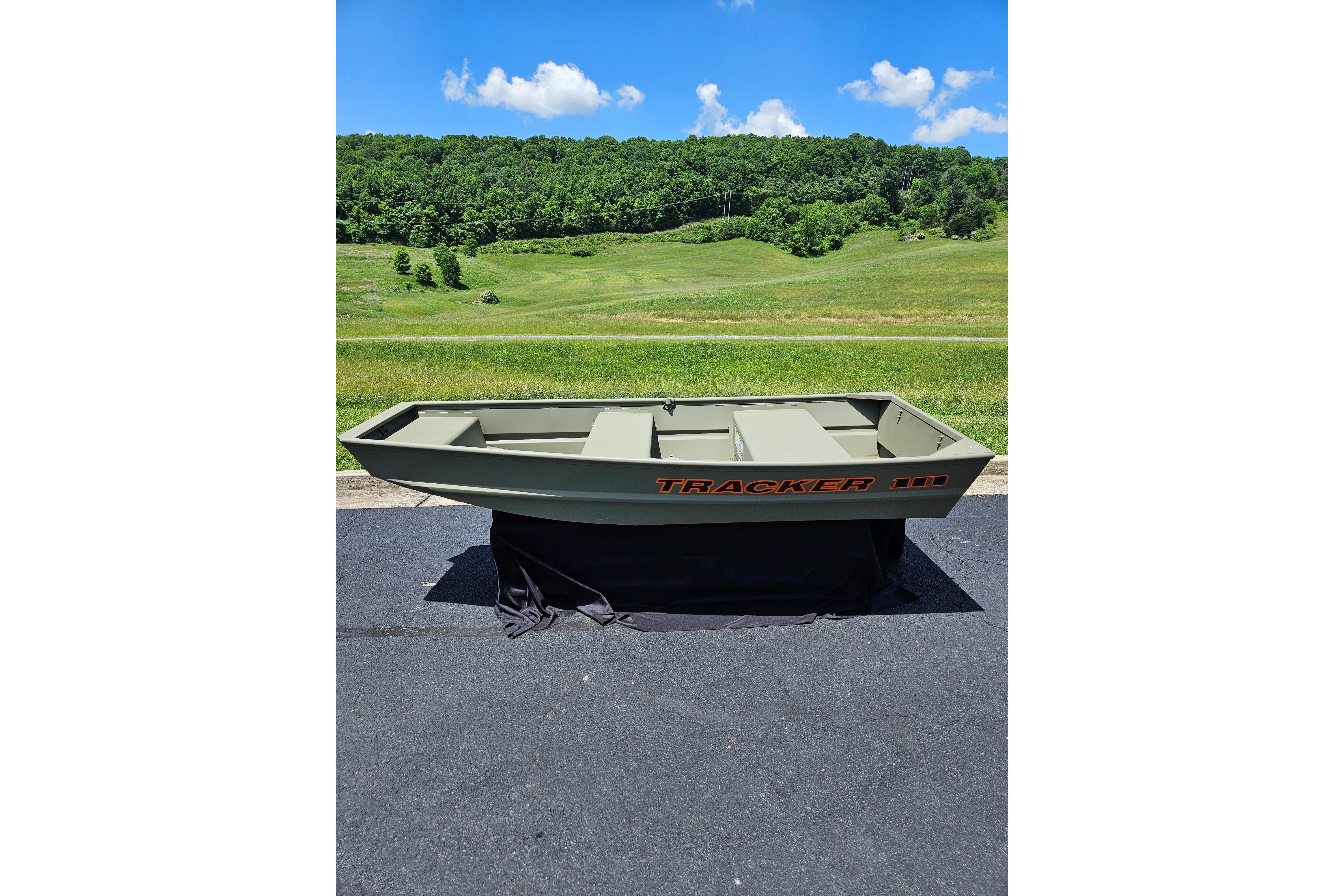 2025 Tracker Grizzly 1036 Utility boat on pavement, green landscape background.