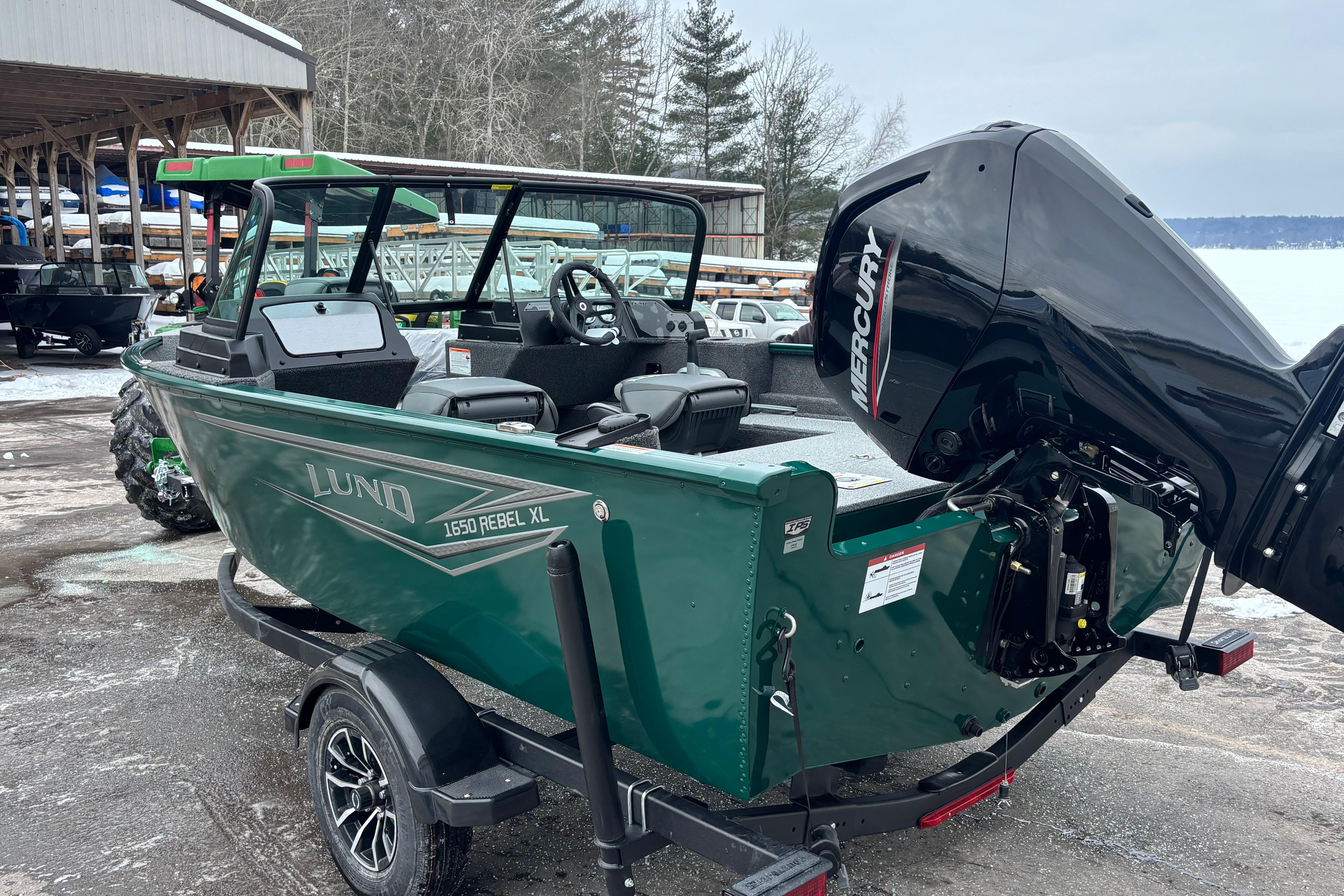2026 Lund 1650 Rebel XL Sport boat with Mercury engine, parked outdoors.