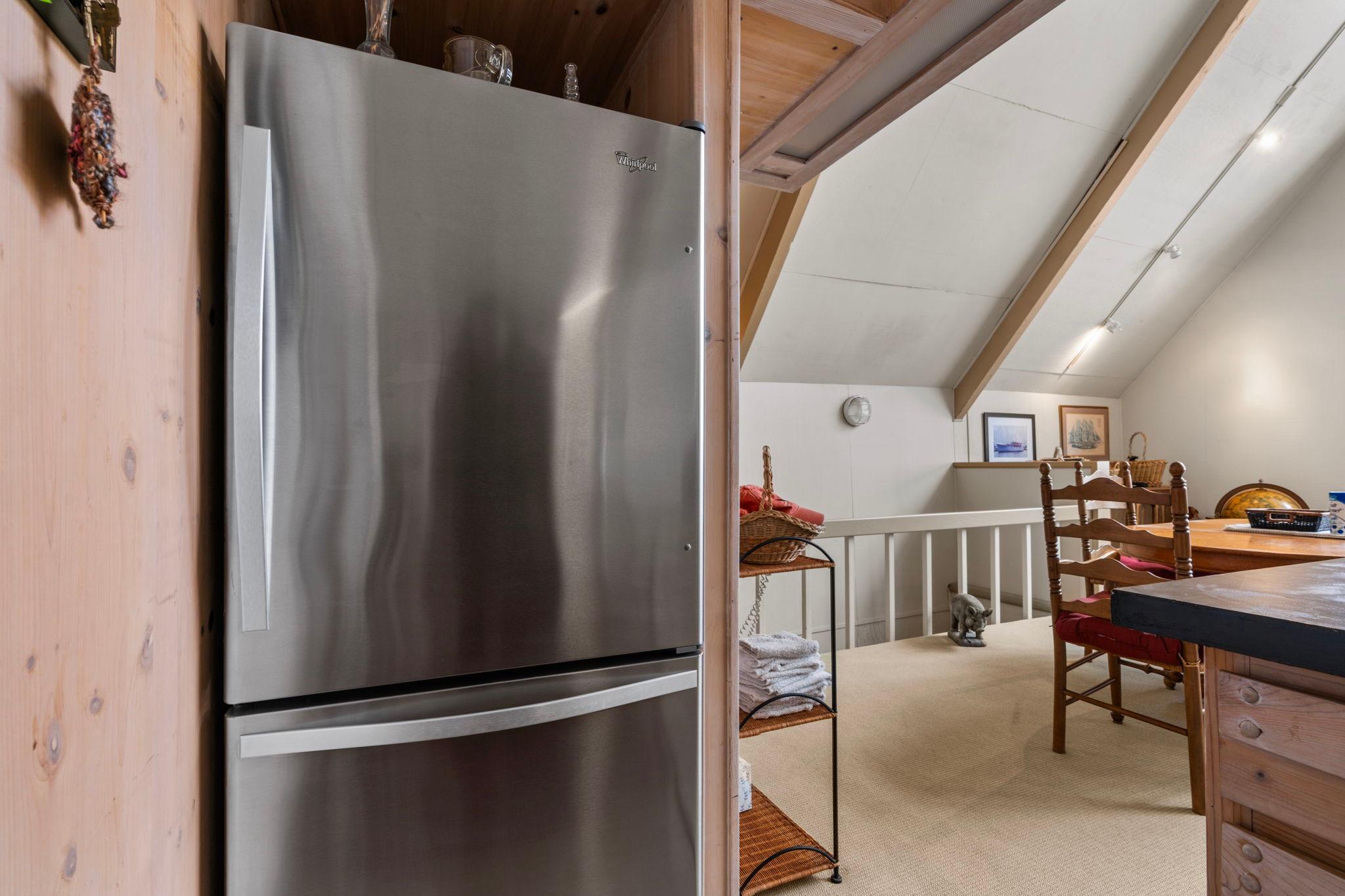 Cozy boathouse interior with stainless steel fridge, wooden beams, and dining area, built in 1976.