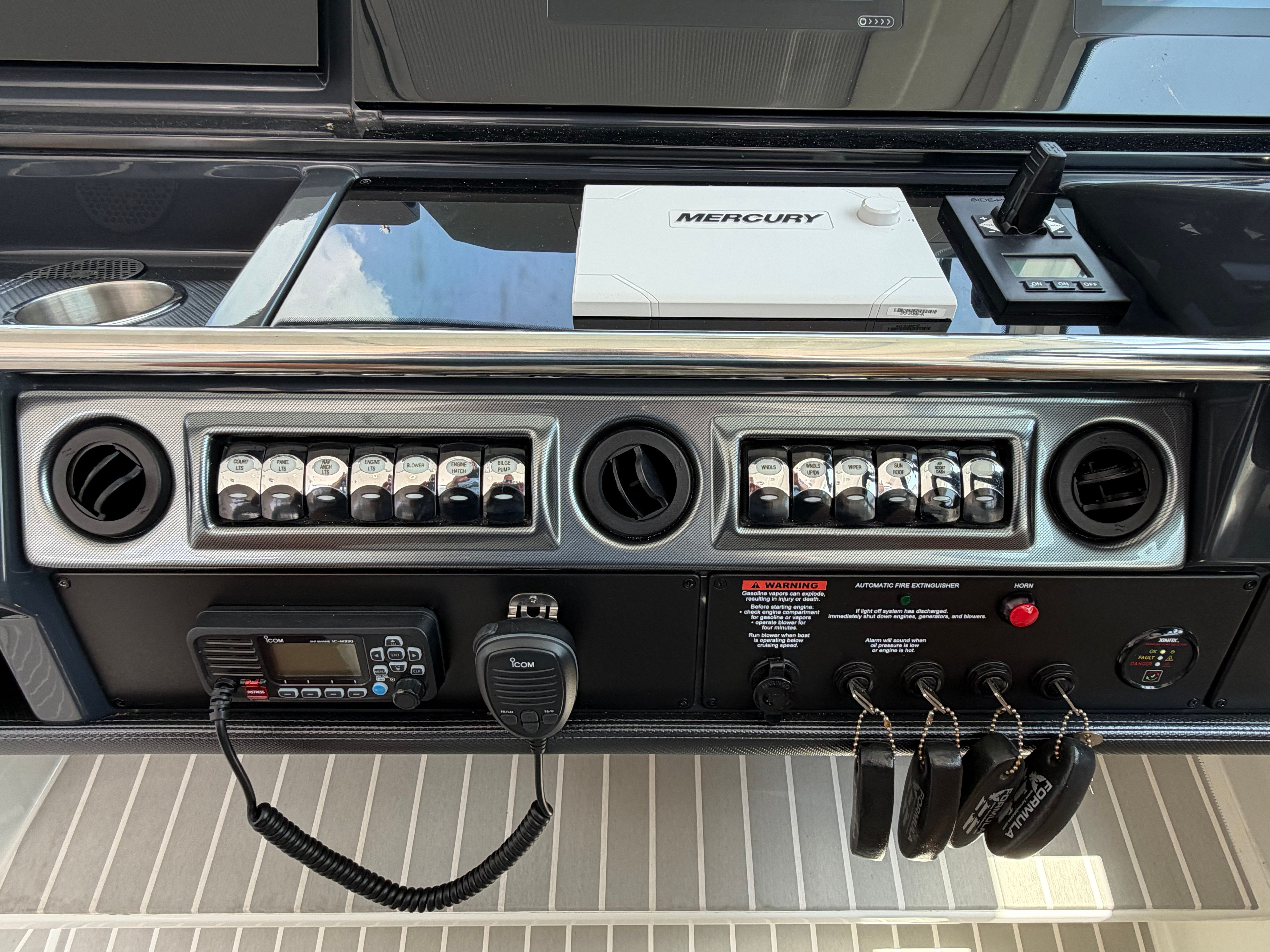 The image shows a boat dashboard with various switches and a radio.
