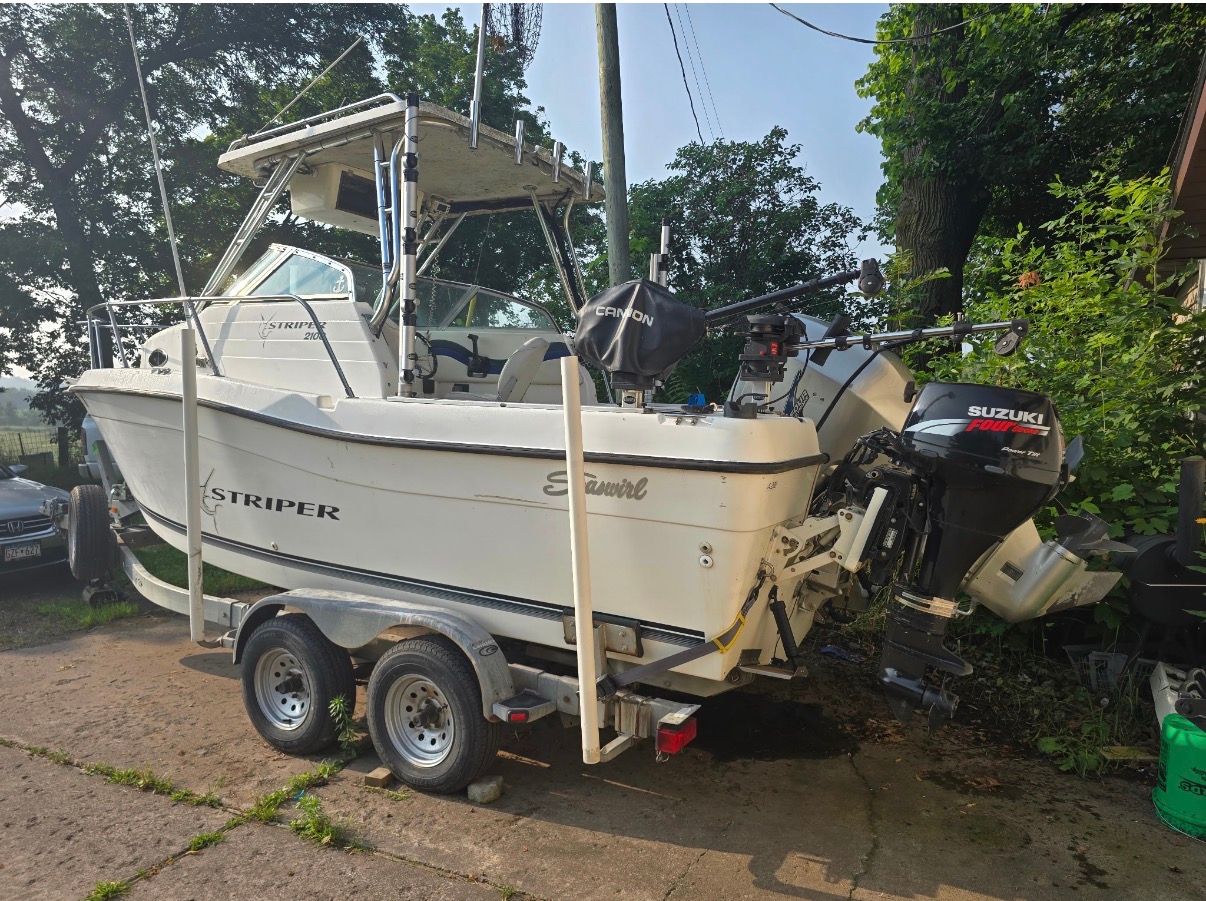A 1999 Seaswirl Striper 2100 on a trailer, with Suzuki outboard motor, parked outdoors.