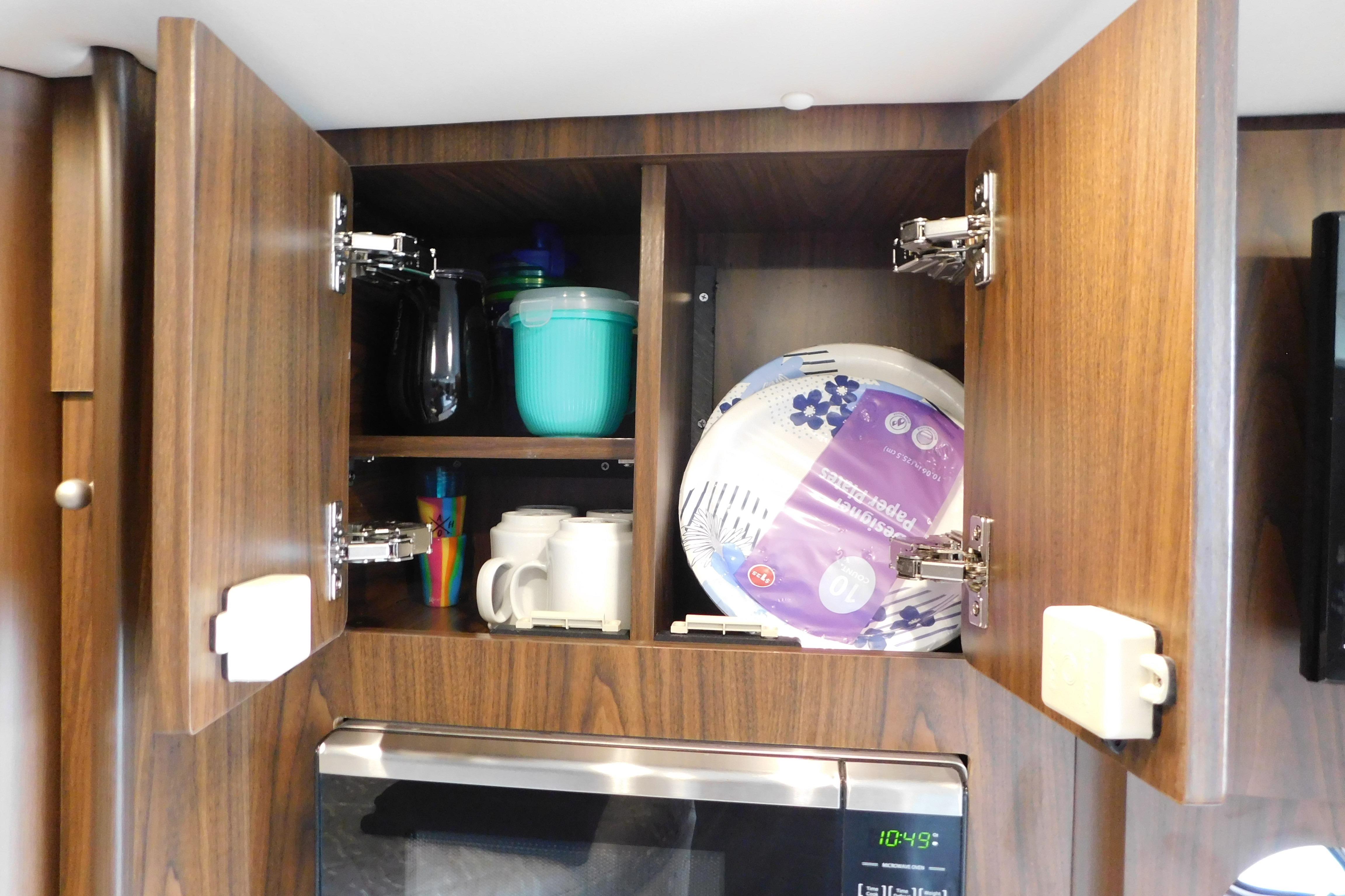2017 Rinker EX 320 kitchen cabinet with mugs, paper plates, and colorful cups.