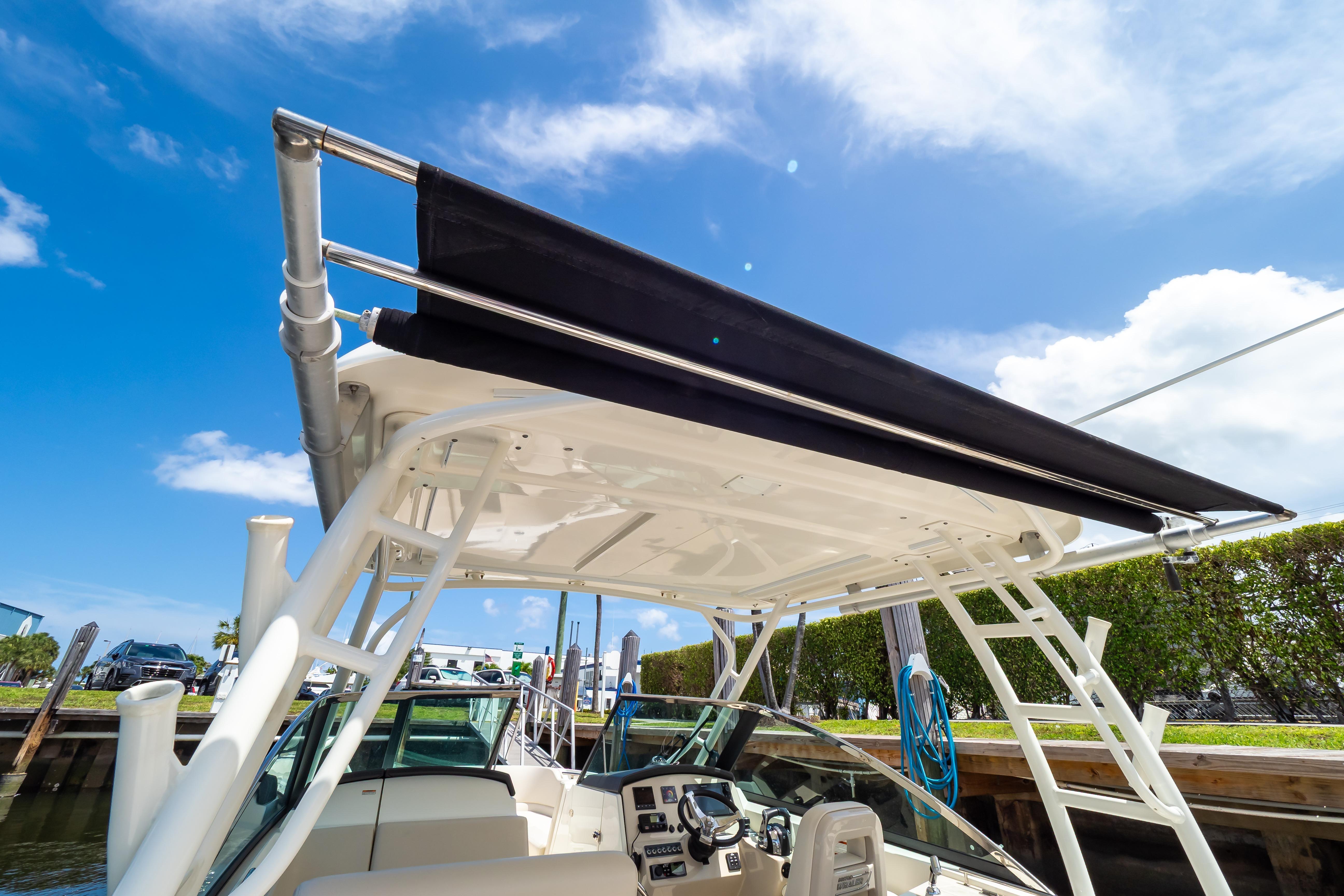 2019 Boston Whaler 270 Vantage boat with canopy, docked under clear blue sky.