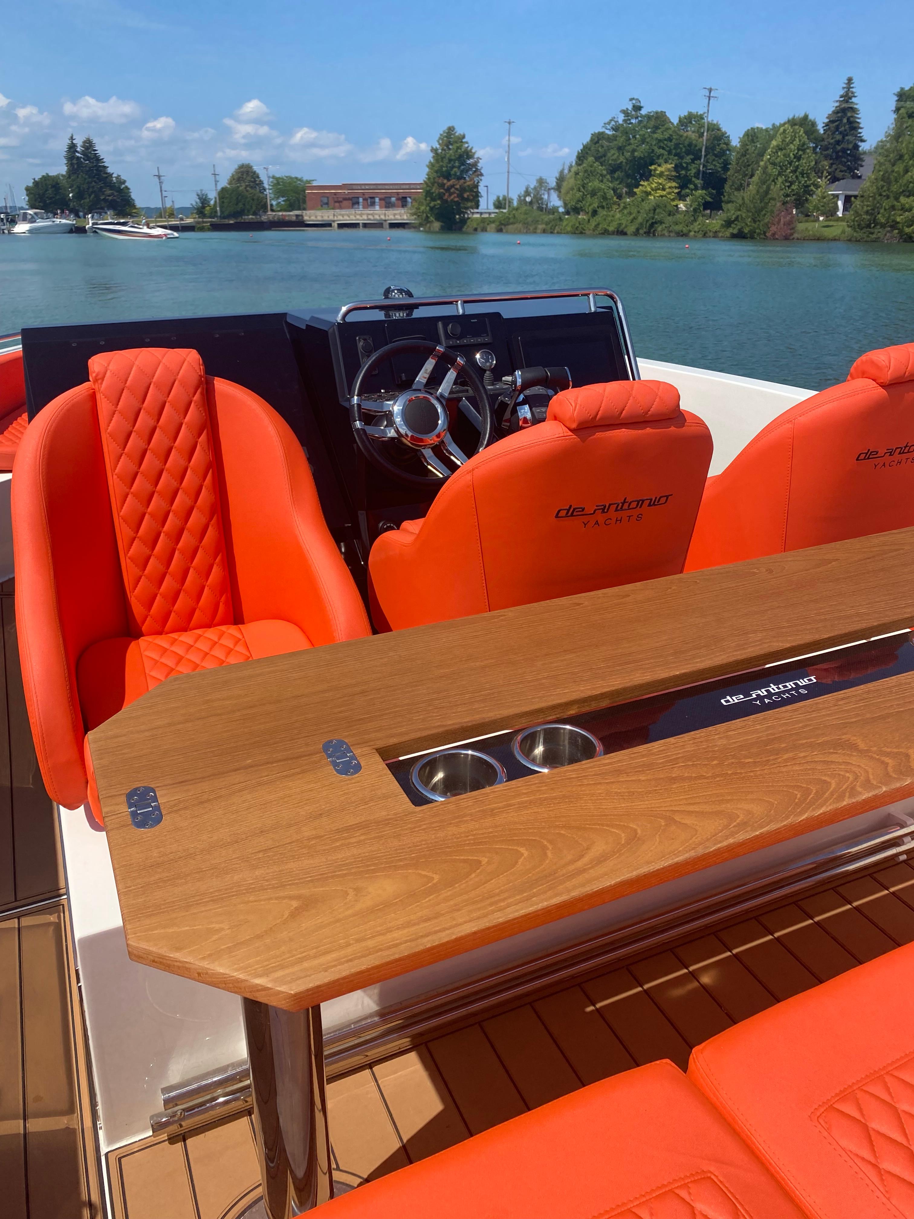 2020 De Antonio Yachts D 28 with orange seating and wooden table on a sunny day.