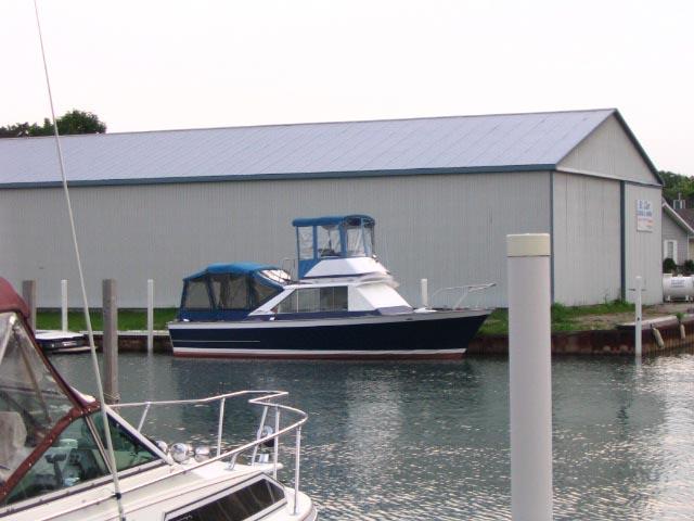 1967 Chris-Craft Sea Skiff 32 Sport Cruiser docked near a boathouse.