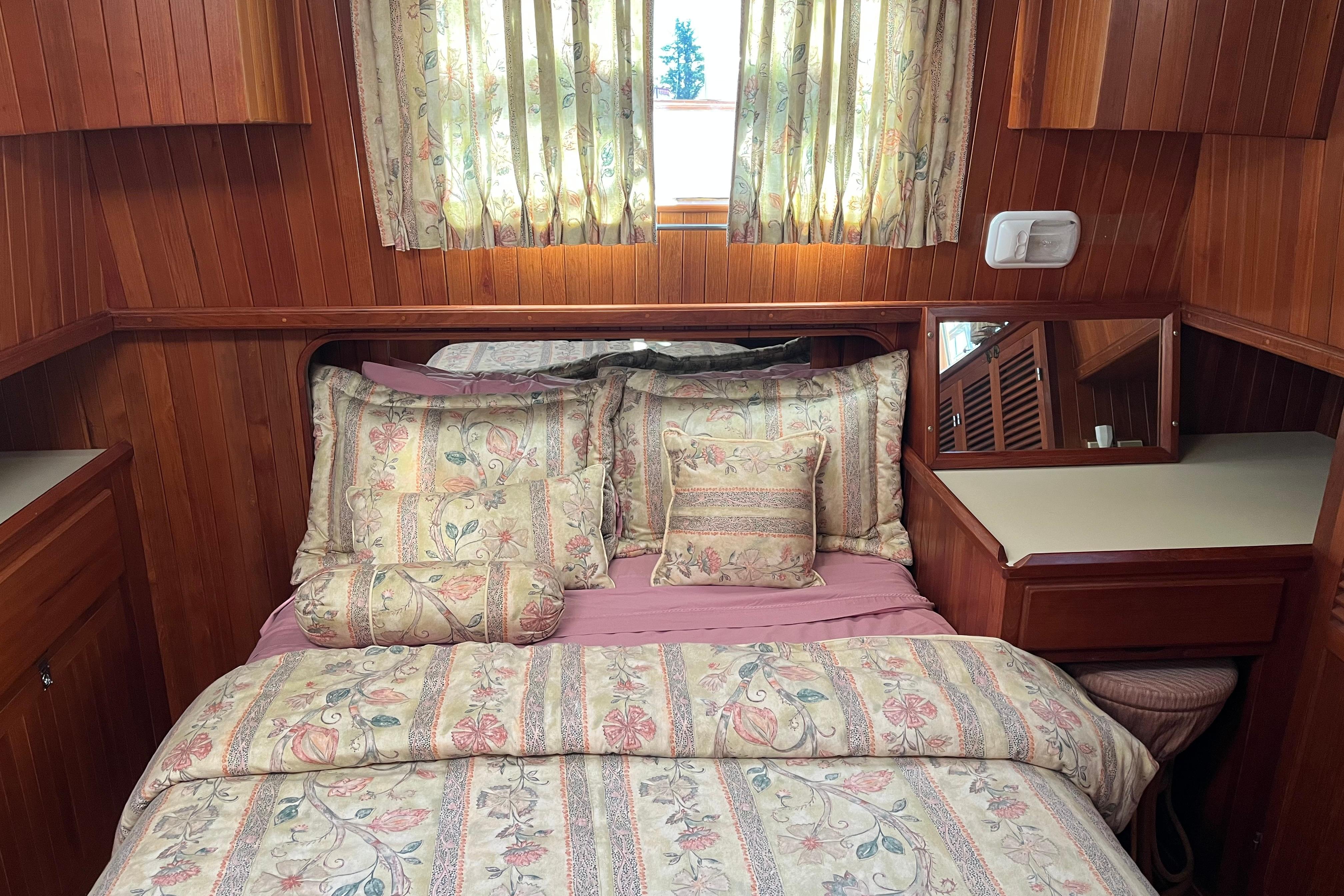 Cozy 1987 Monk 36 boat cabin with floral bedding and wooden interior.