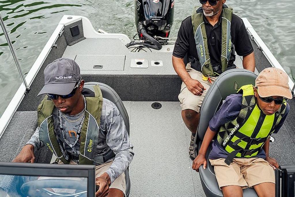 2026 Lowe Fishing Machine 175 with three passengers wearing life jackets on a lake.