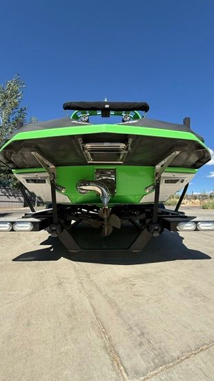 The image shows the rear of a green boat on a trailer.