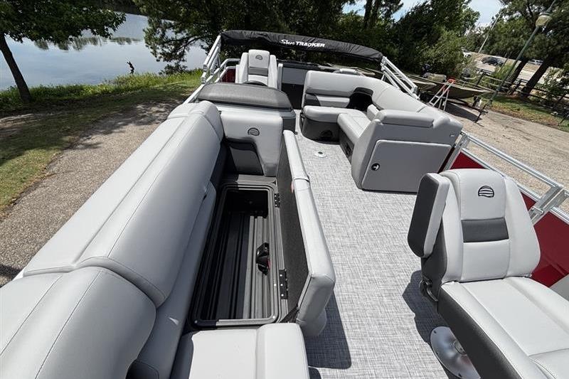 2026 Sun Tracker SportFish 20 DLX pontoon boat with spacious seating and storage, docked by a lake.
