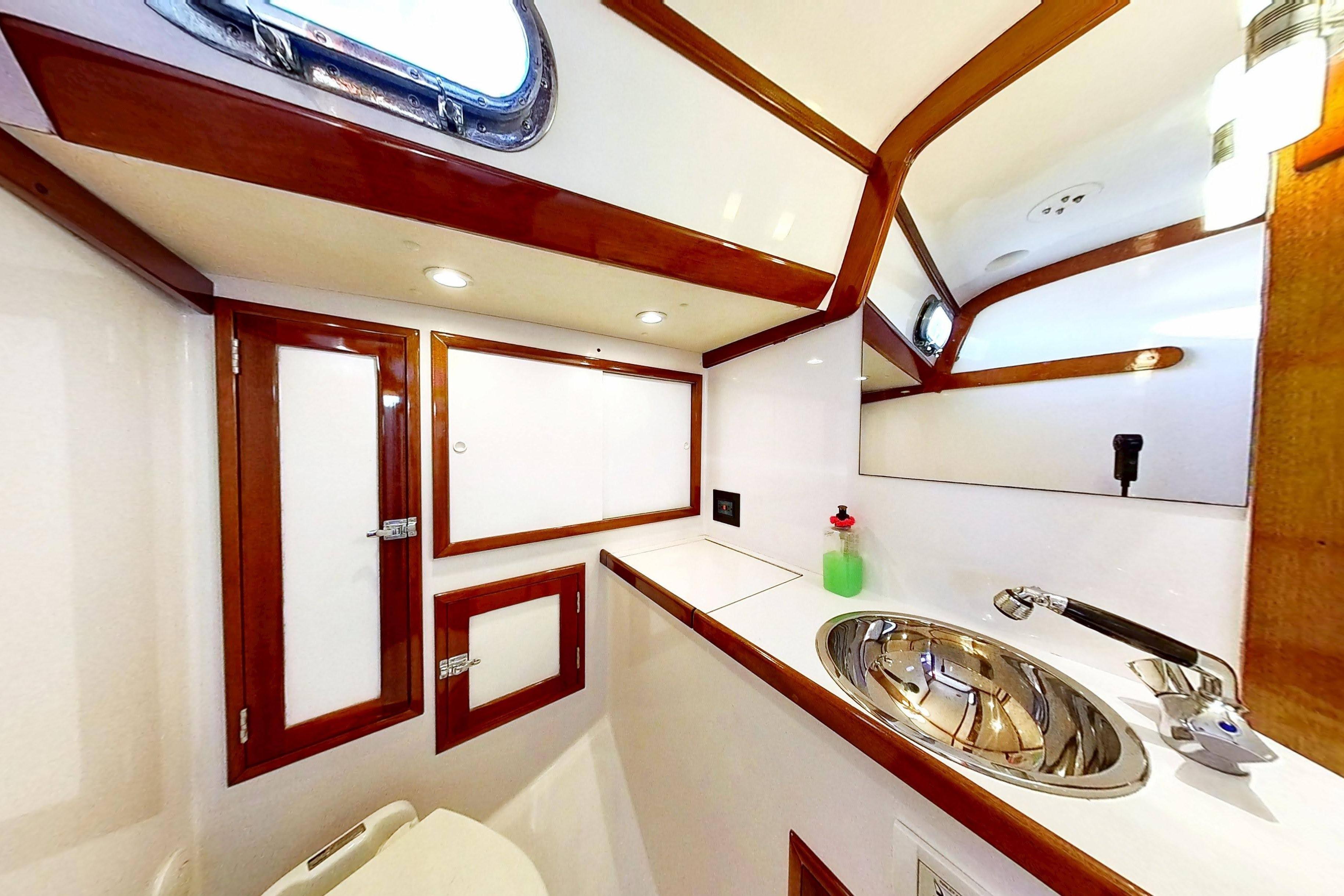 Interior of 1970 Hinckley Bermuda 40 yacht bathroom with wood accents and stainless steel sink.