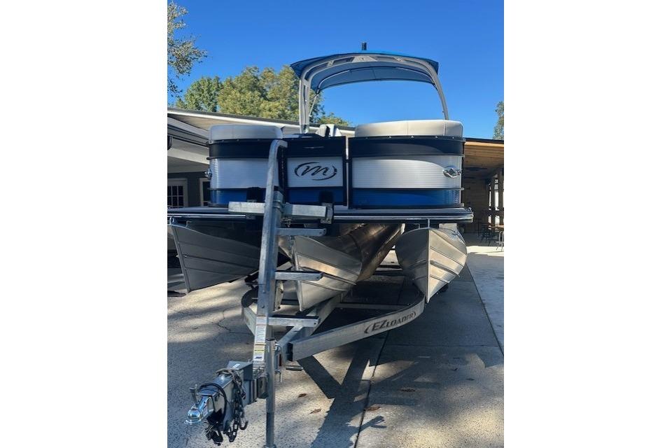 2020 Manitou 25 X-Plode RFW pontoon boat on trailer, parked outdoors.