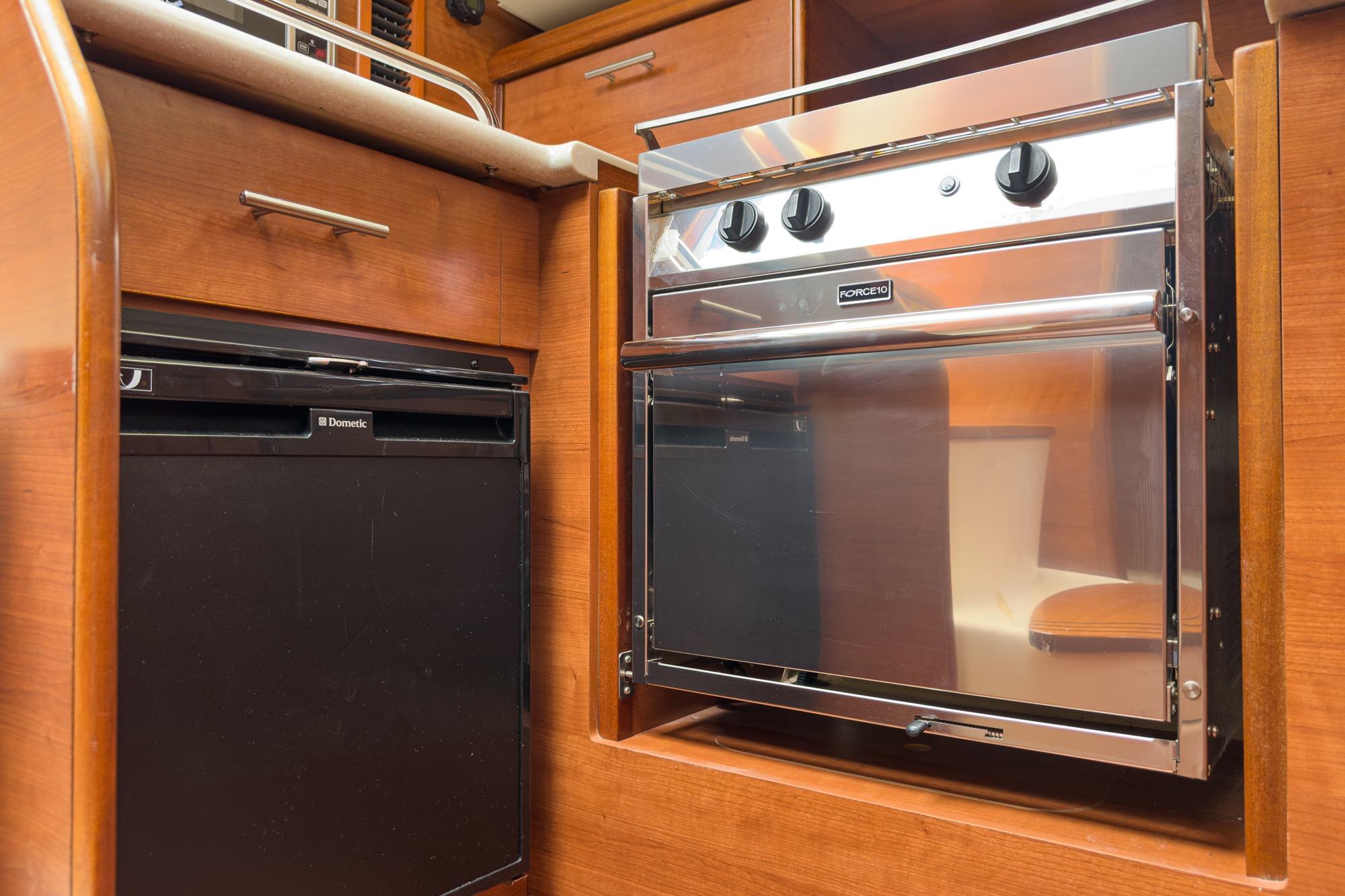 Compact kitchen area in a 2015 Hunter 33 yacht with oven and fridge.
