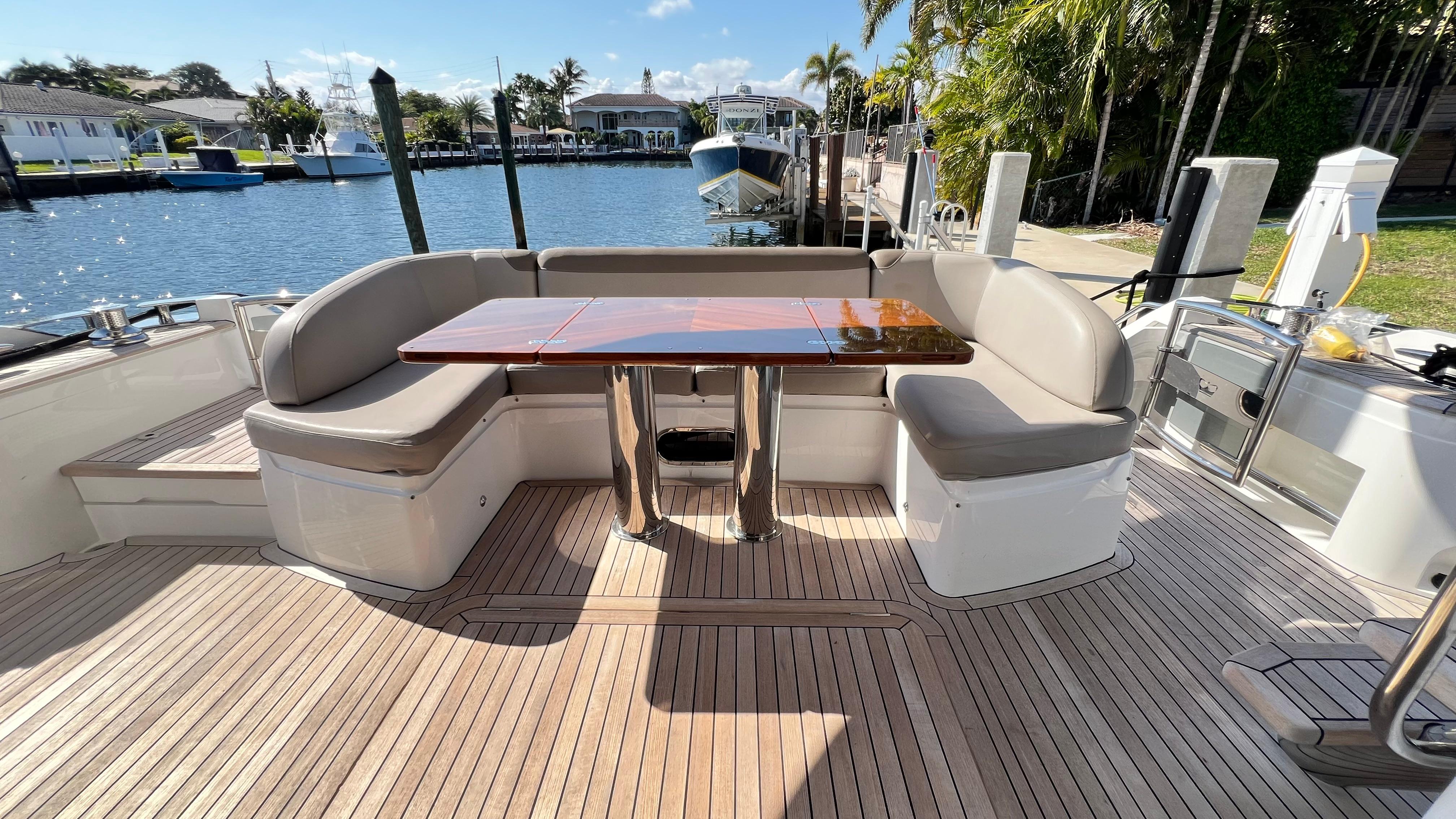 Luxurious 2019 Princess F62 yacht deck with elegant seating and wooden table by the water.