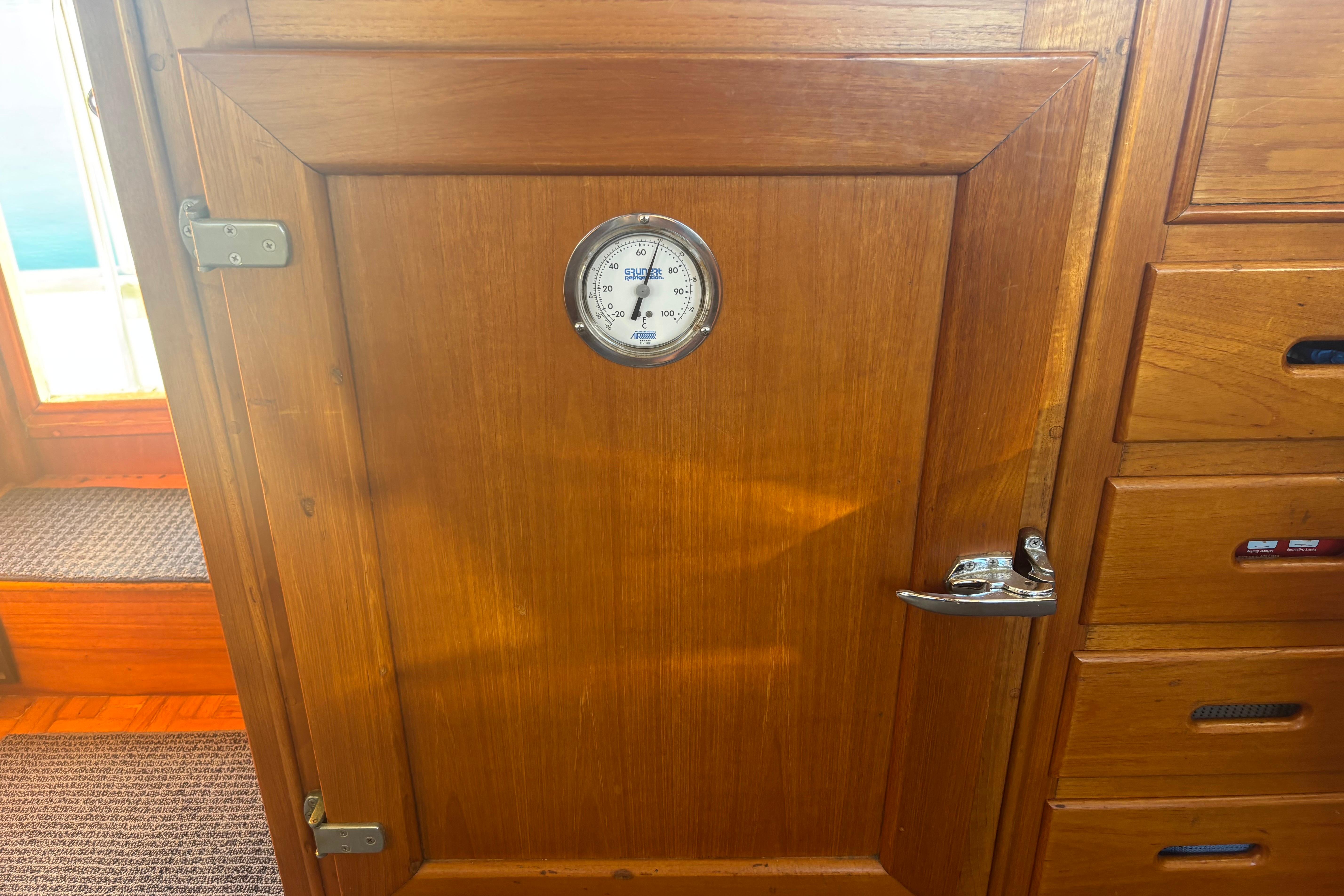 Wooden interior of 1989 Grand Banks 46 Classic with thermometer on cabinet door.