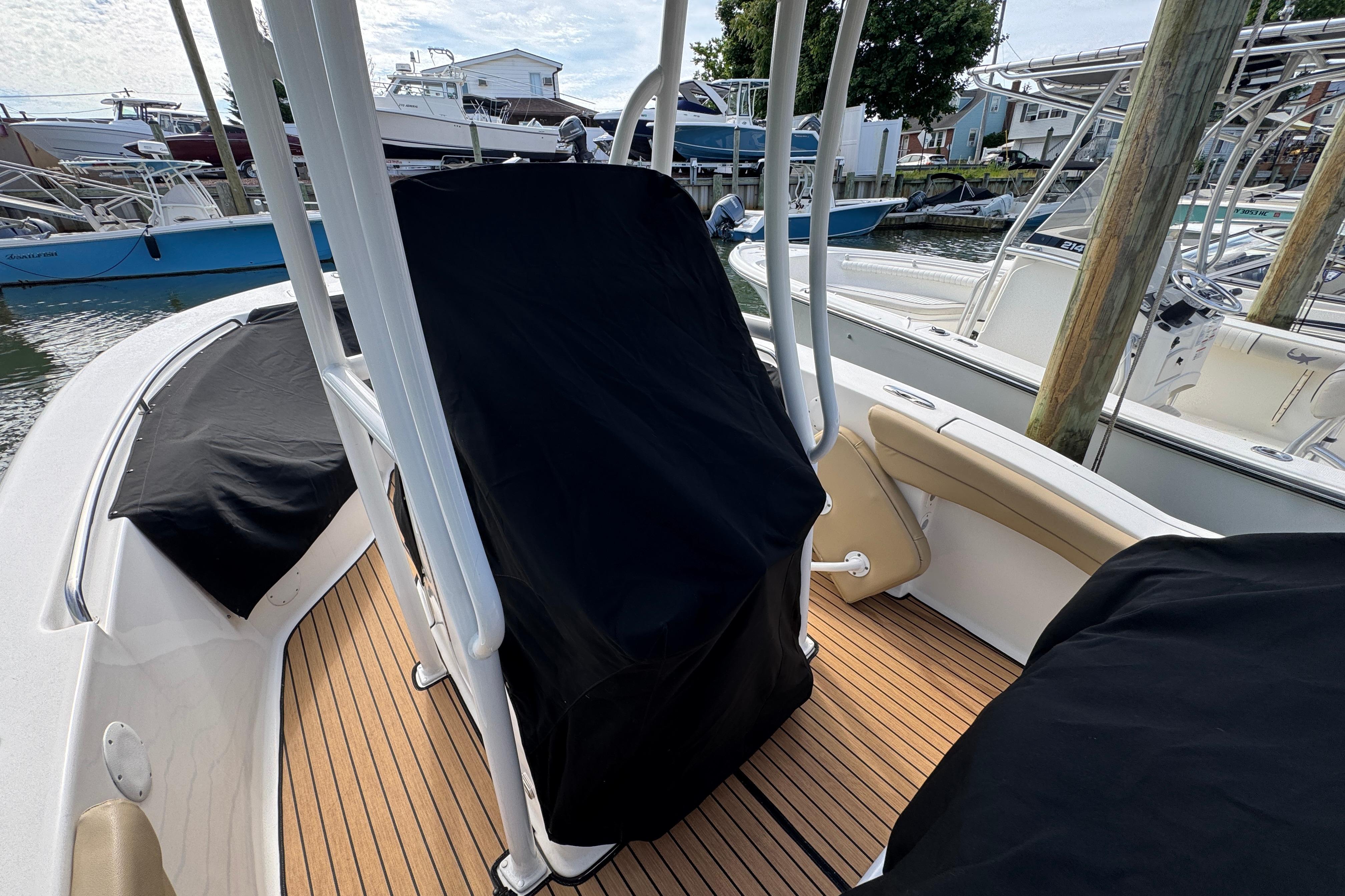 2016 Tidewater 230 LXF boat interior with covered seating and teak flooring at a marina.