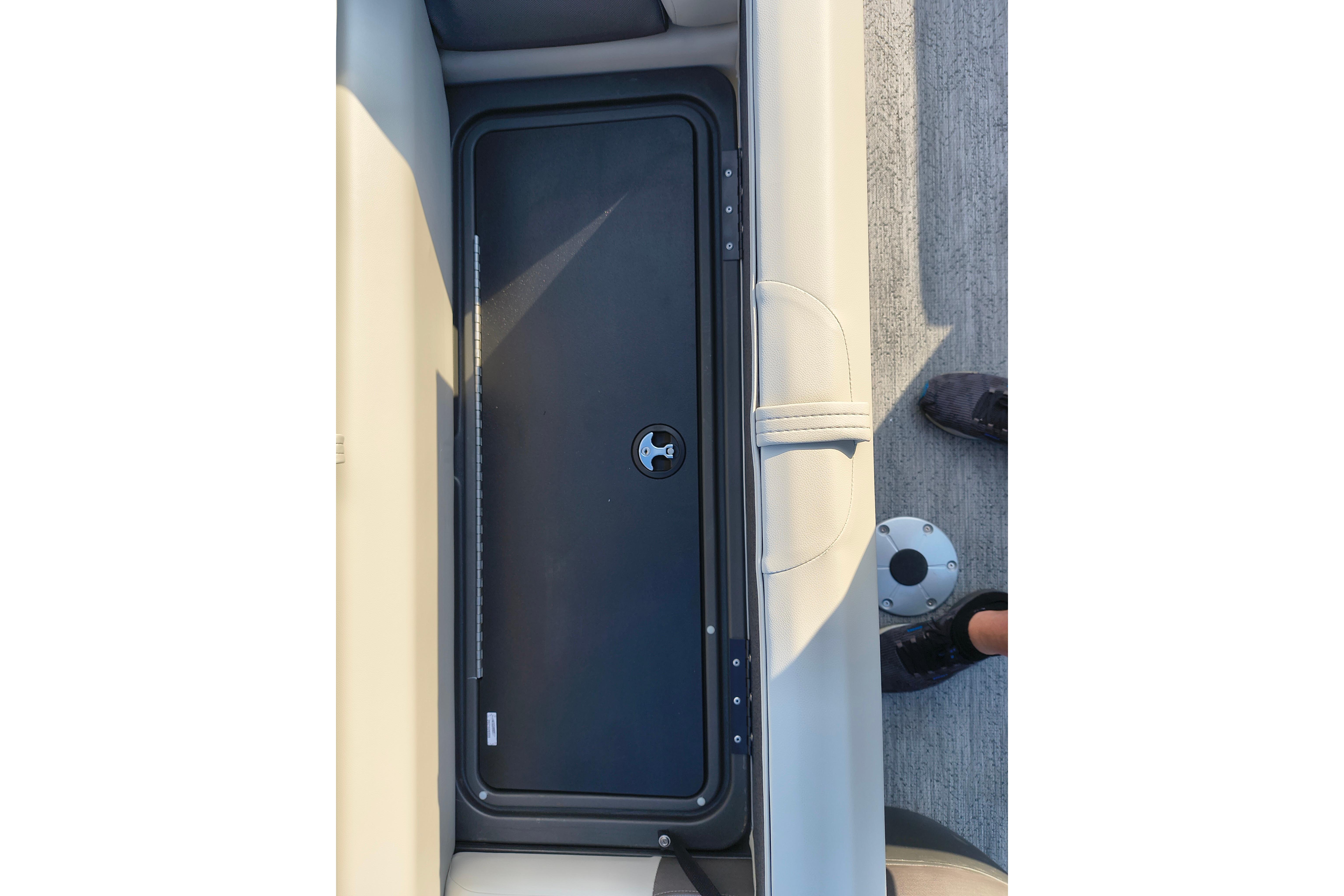 2026 Sun Tracker Fishin' Barge 22 DLX storage compartment with beige seating and black lid.