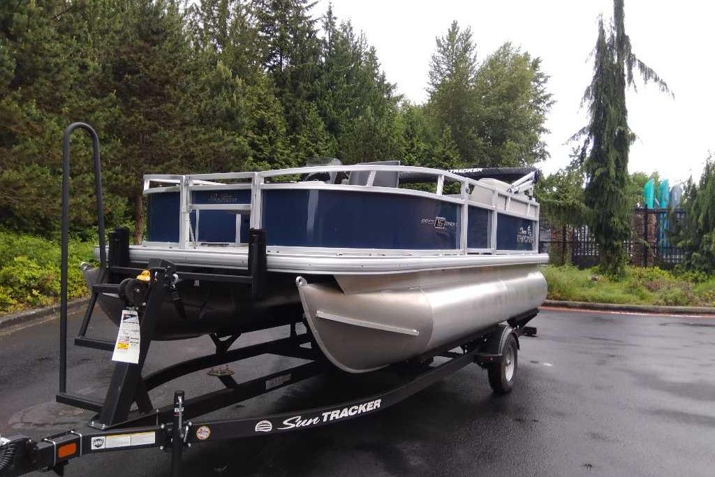 2026 Sun Tracker Bass Buggy 16 XL Select pontoon boat on trailer, parked outdoors.