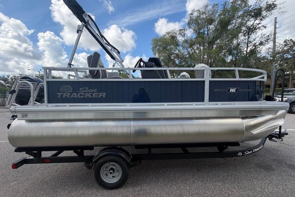 2026 Sun Tracker Bass Buggy 16 XL Select pontoon boat on trailer, parked outdoors.