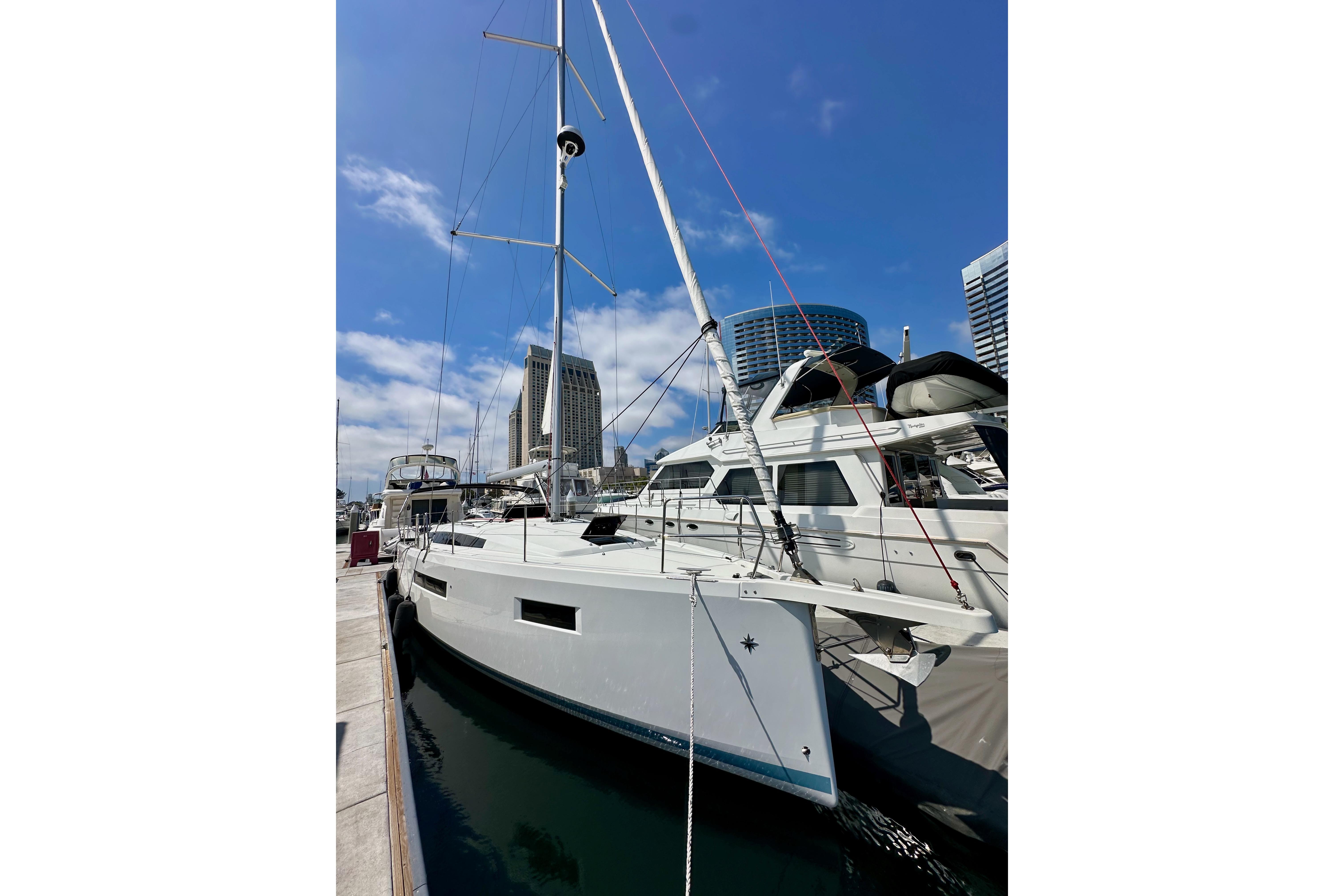 2024 Jeanneau Sun Odyssey 410 sailboat docked in marina, clear blue sky background.