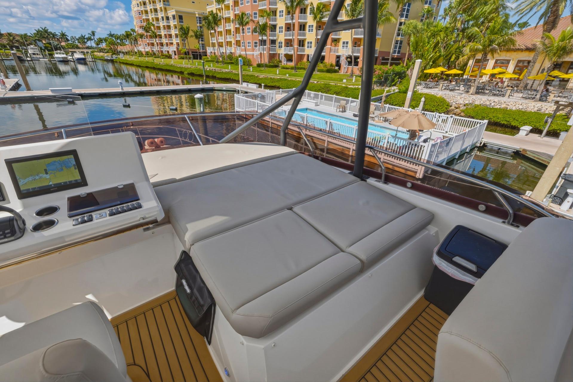 Flybridge of 2022 Prestige 520 yacht with seating, control panel, and marina view.