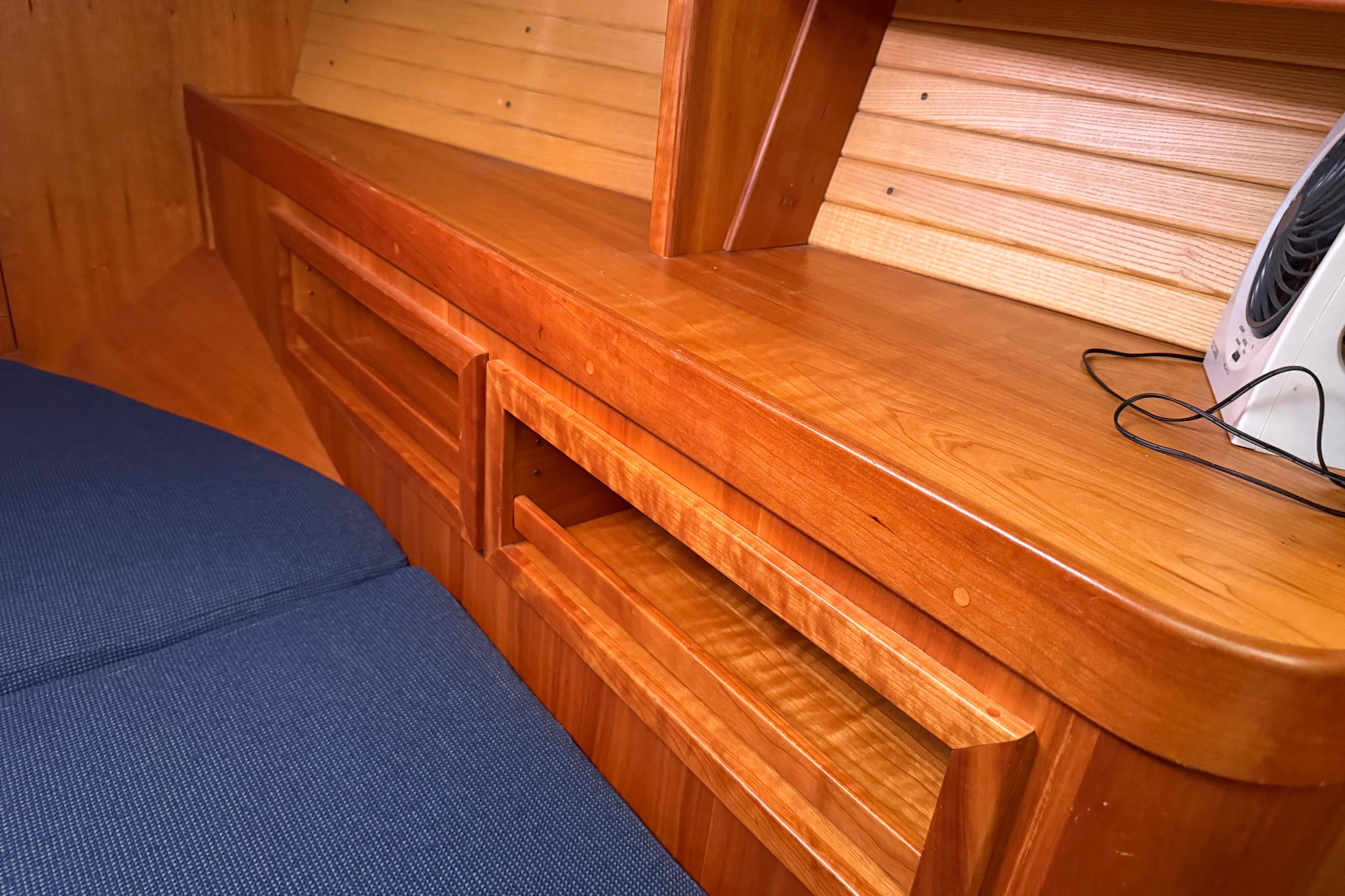 Wooden interior of a 2004 Sabre 386 yacht with blue upholstery and built-in storage.