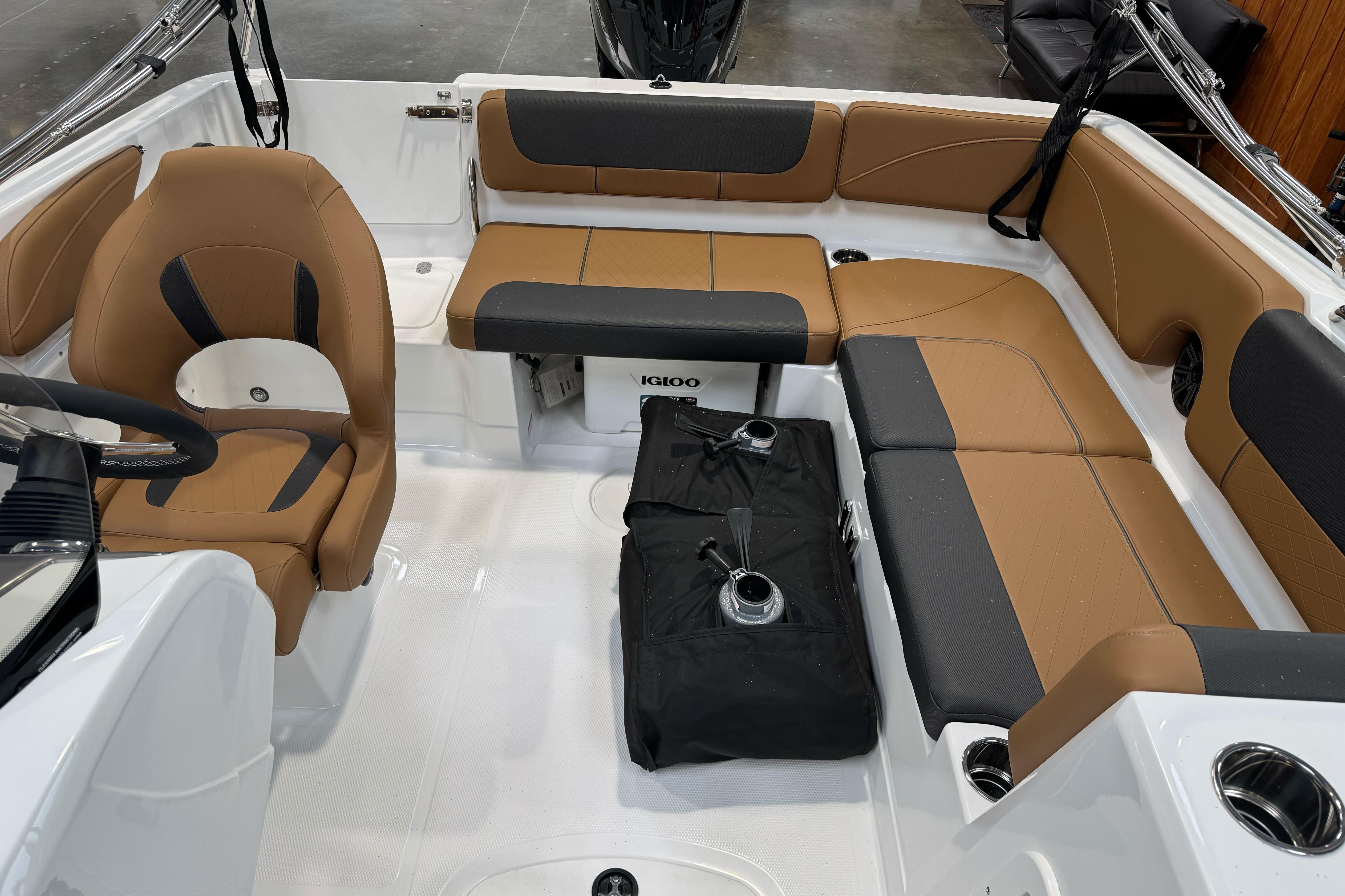 2026 Tahoe 2150 boat interior with tan and black seating, steering wheel, and storage area.