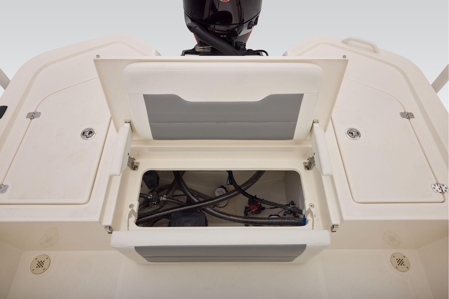 Open storage compartment on 2026 Mako 24 APEX boat, showing internal wiring and components.