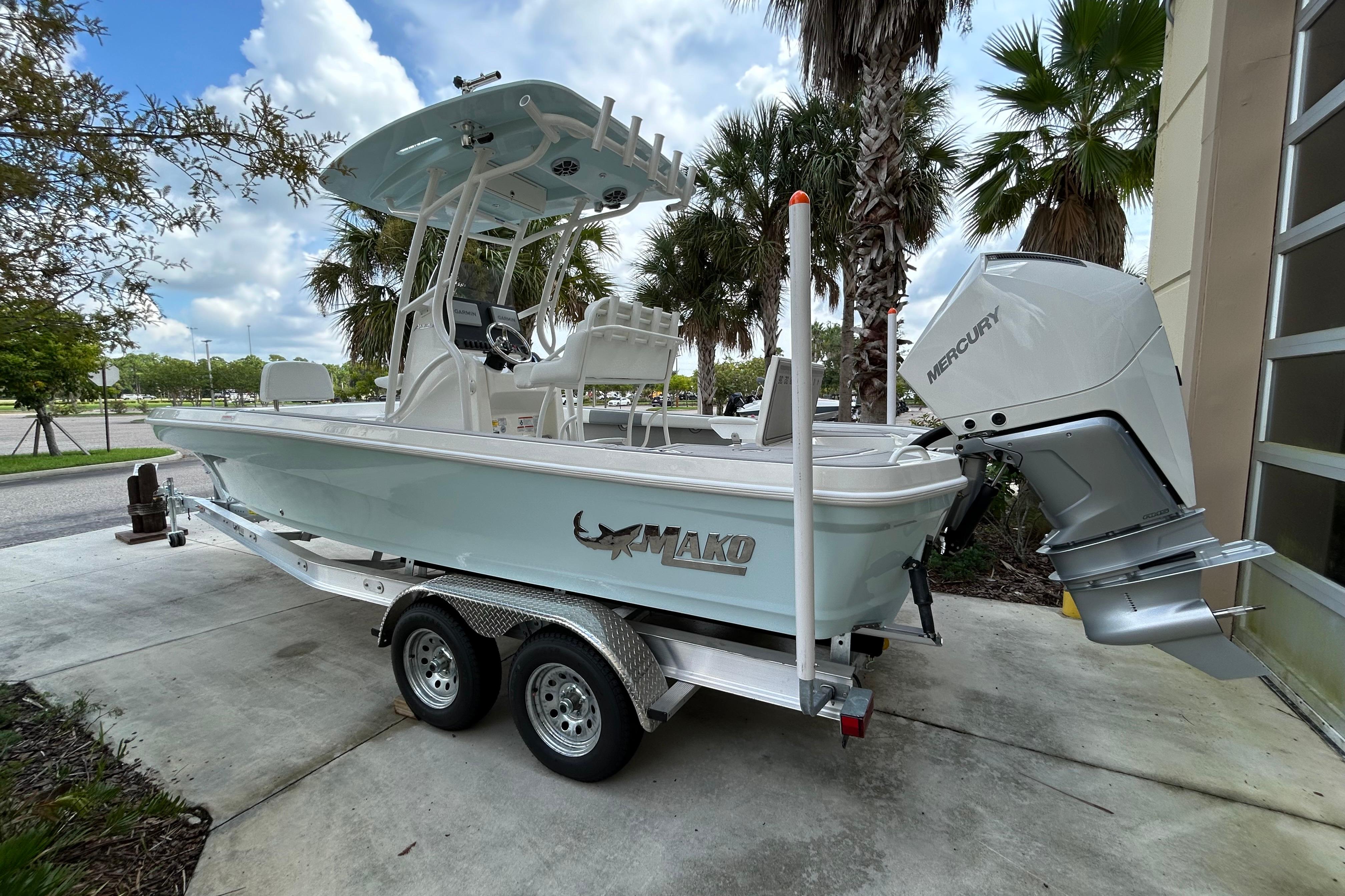 2025 Mako 24 APEX boat on trailer, featuring Mercury outboard motor, parked outdoors.
