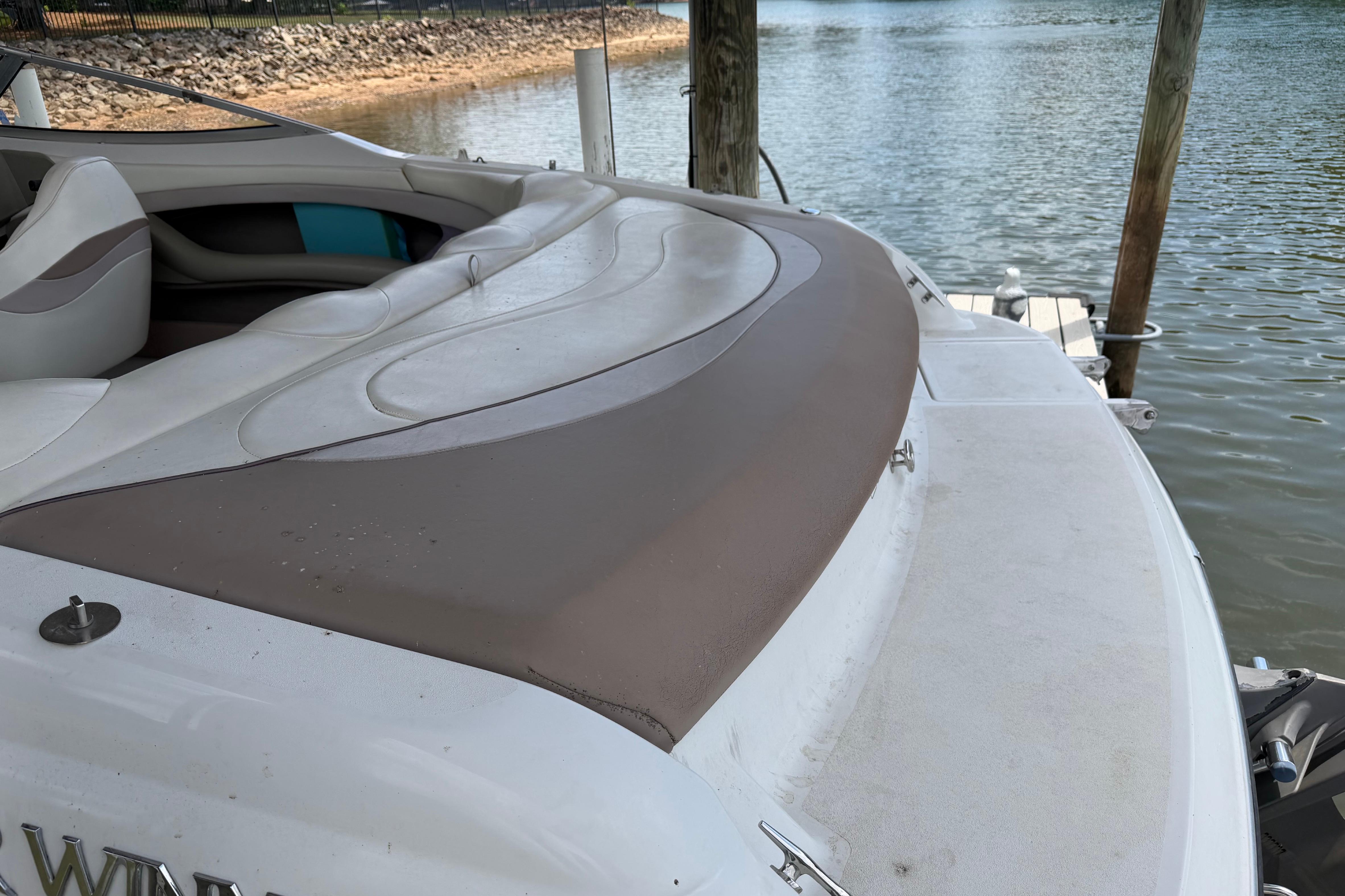 1998 Four Winns 220 Horizon boat with cushioned seating, docked by a calm lake.