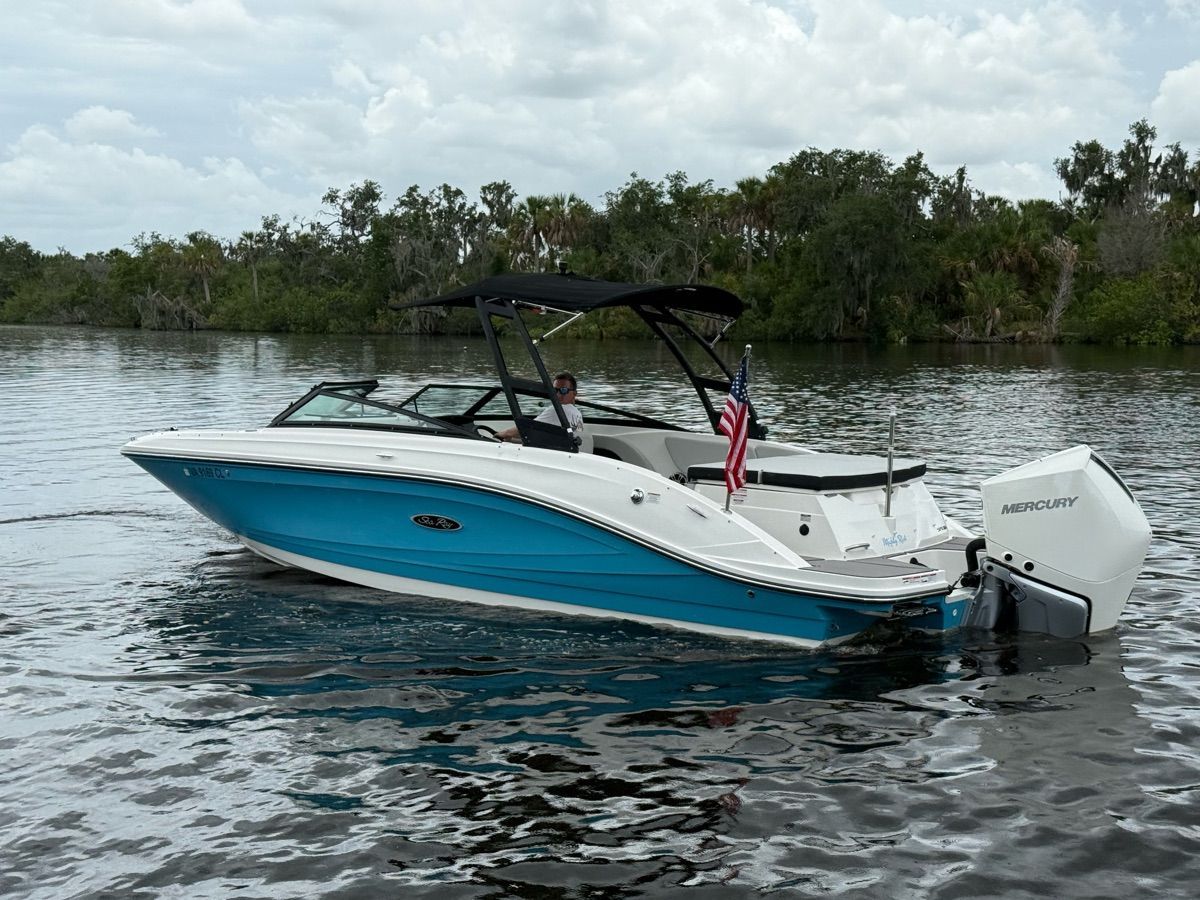 A 2024 Sea Ray SPX 230 Outboard cruising on calm waters, surrounded by trees.