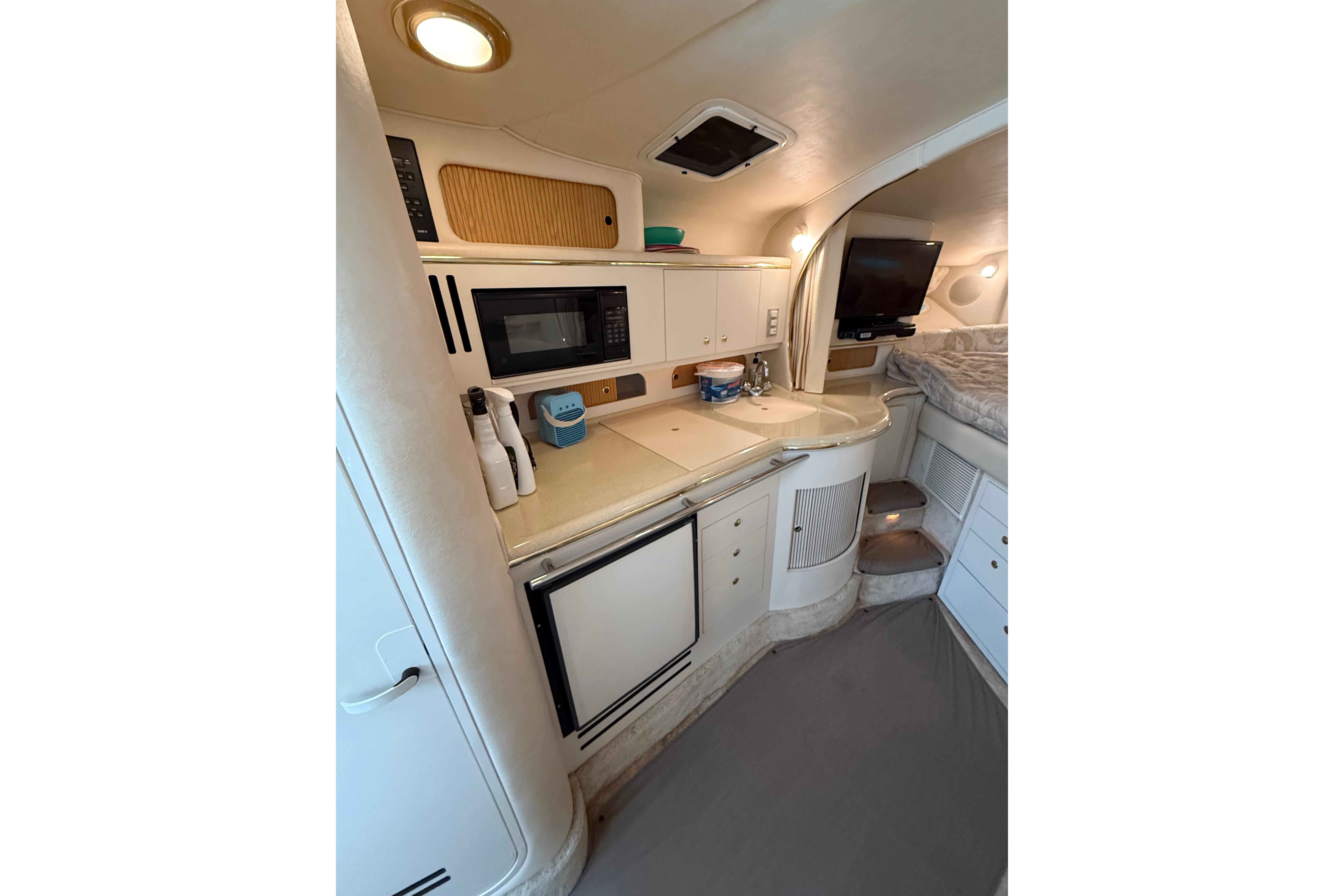 1999 Sea Ray Sundancer 310 interior with kitchenette, microwave, and cozy sleeping area.