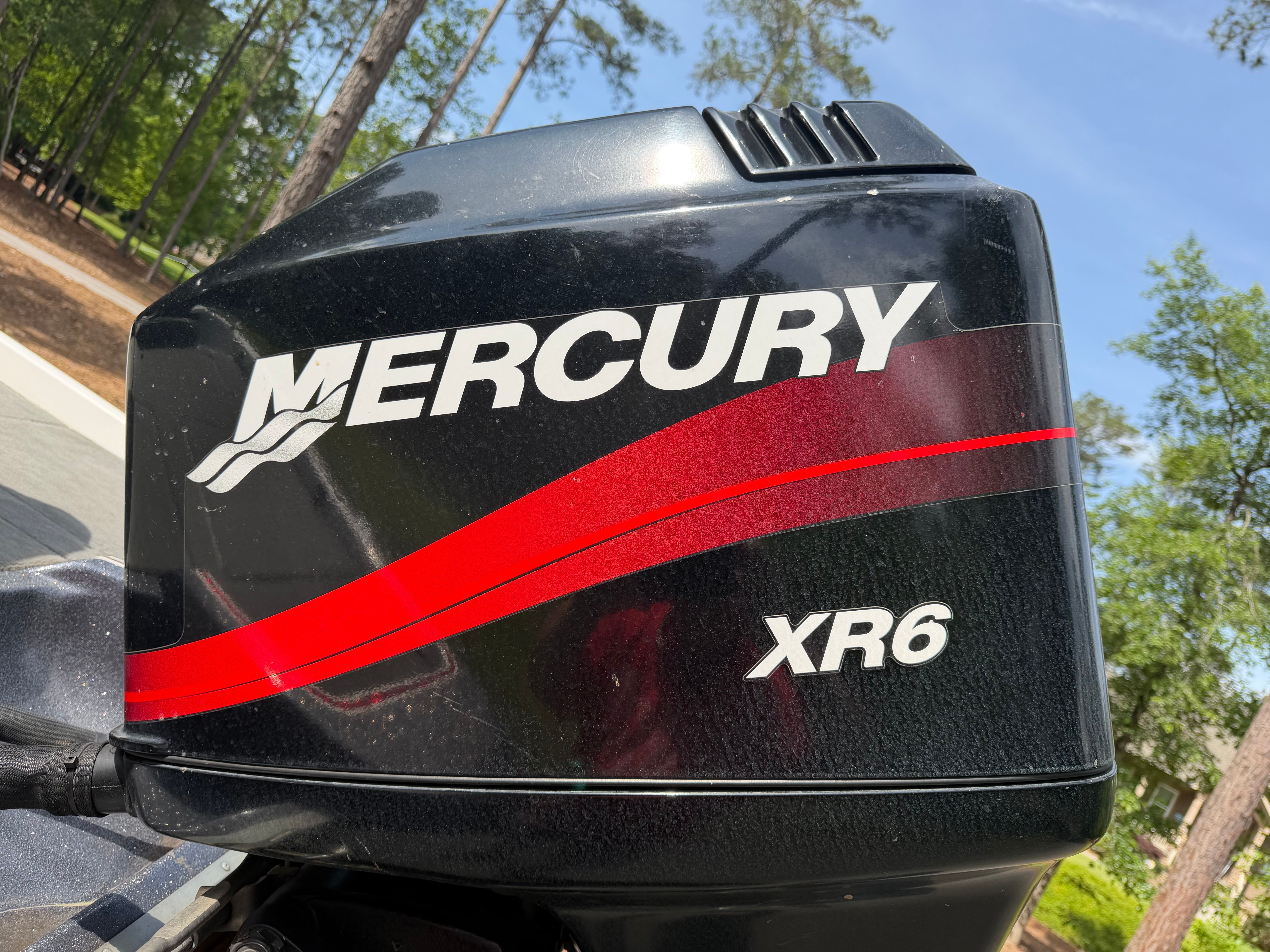 A Mercury XR6 outboard motor is mounted on a boat. The motor has a black casing with red accents.