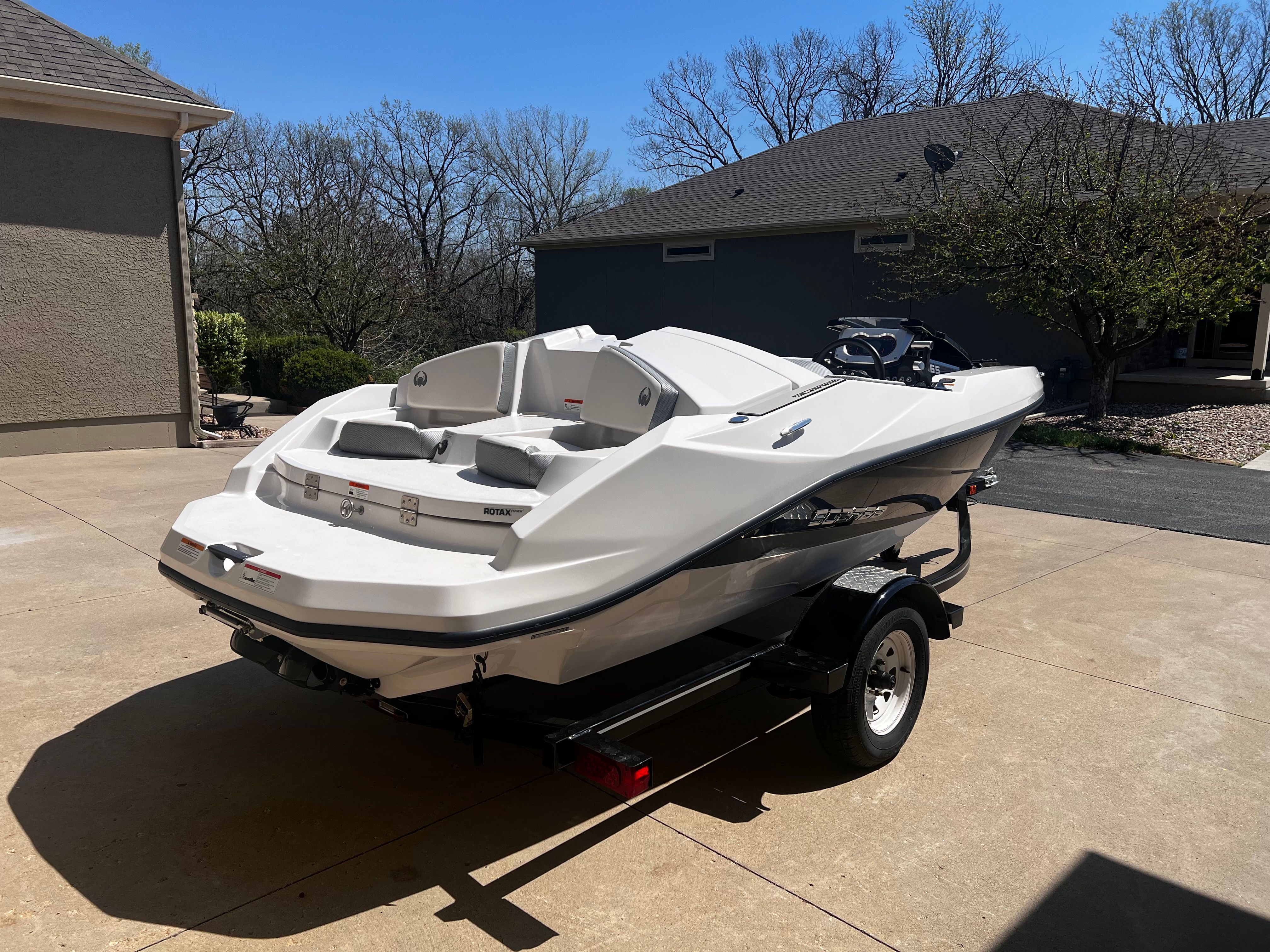 A white 2019 Scarab 165 G boat is on a trailer in a driveway.