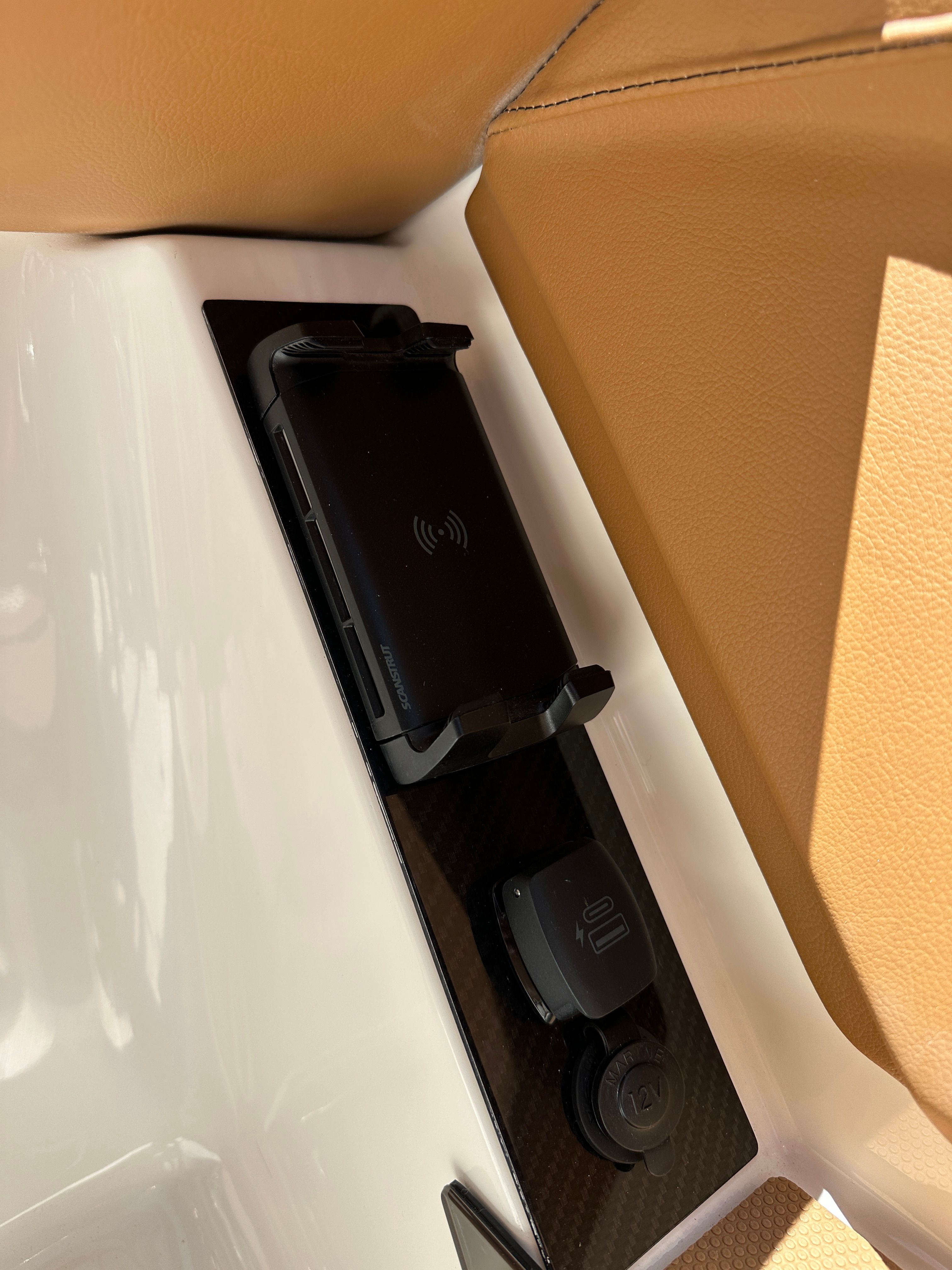 A wireless charger and outlets are integrated into the brown upholstery of a boat.
