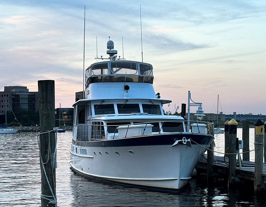 An elegant white yacht docked at sunset, with a calm water backdrop.