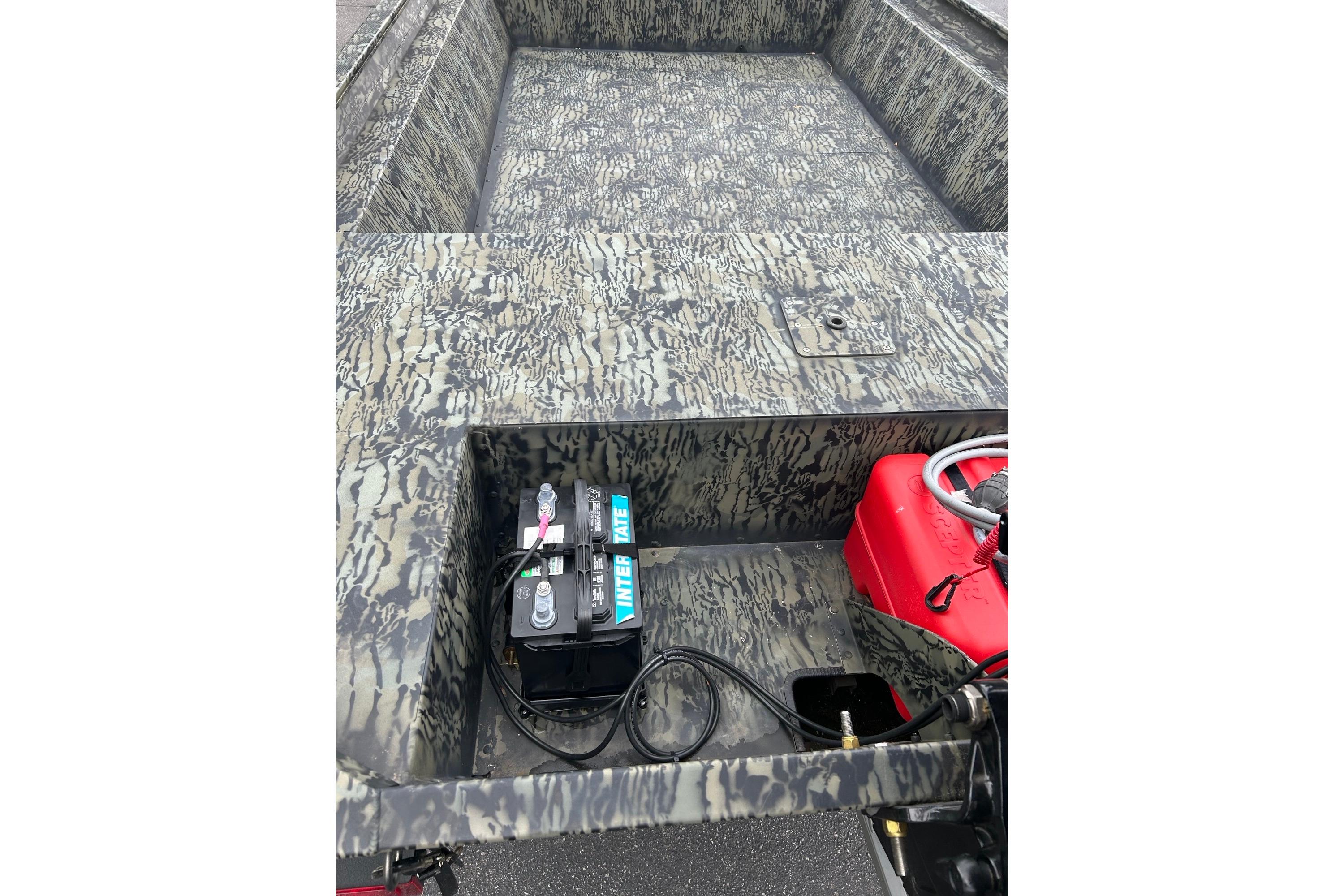 2025 Tracker Grizzly 1860 AWL boat interior with camouflage design, battery, and red fuel tank.