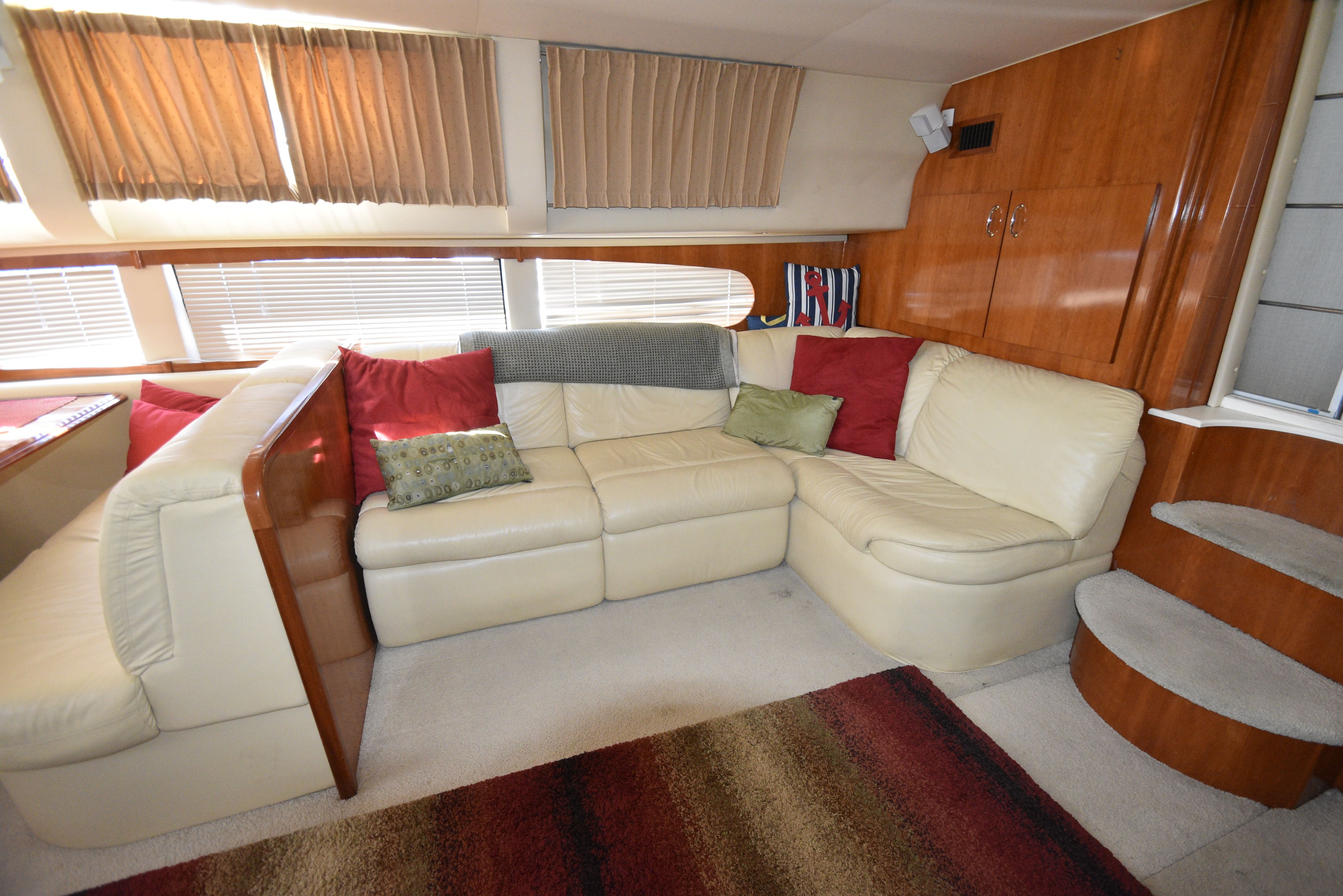 Interior of a 2004 Carver 466 Motor Yacht with beige sofa and red cushions.