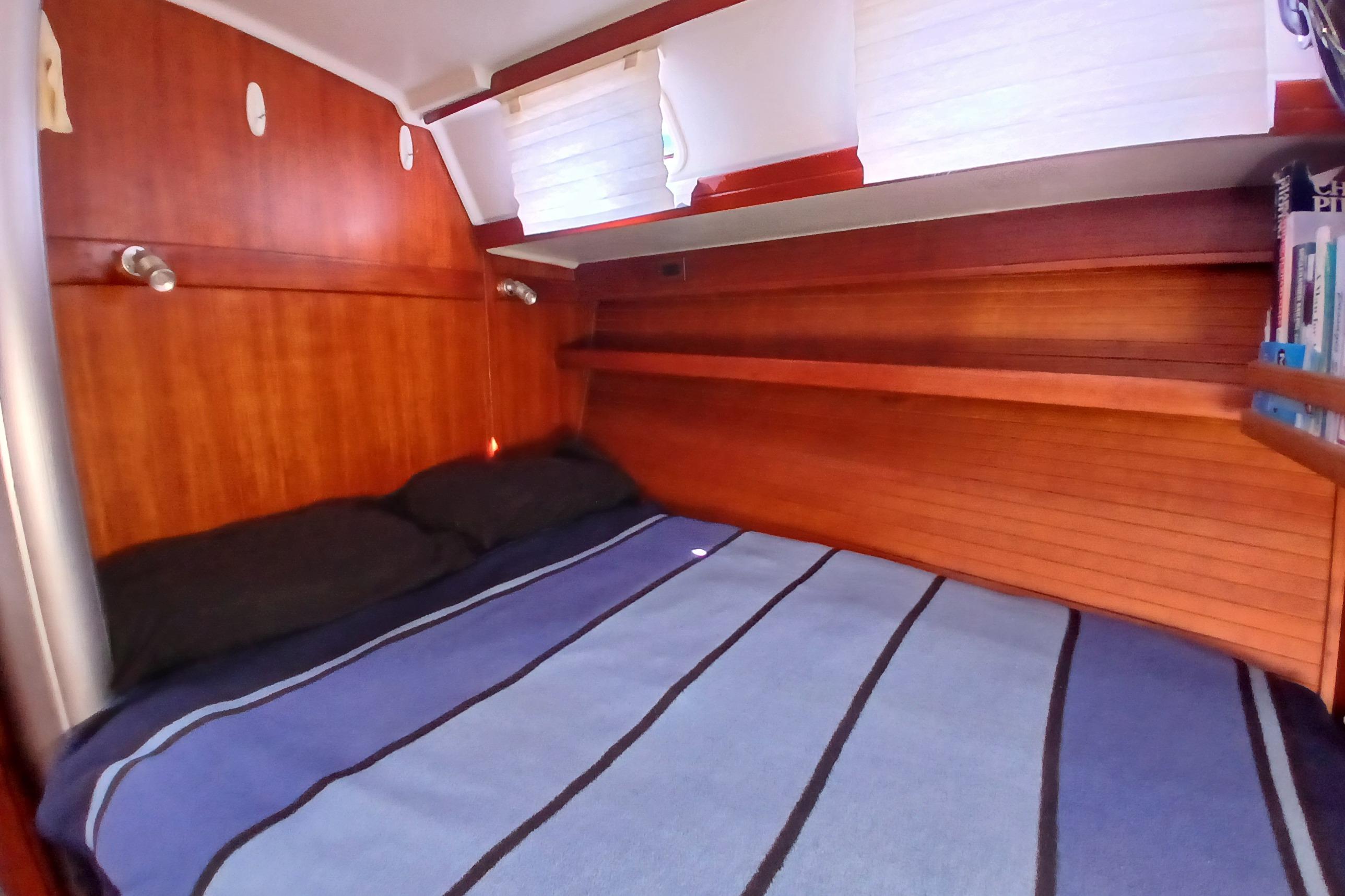 Cozy cabin interior of 1995 Catalina 42 MkII sailboat with wooden finish and striped bedding.